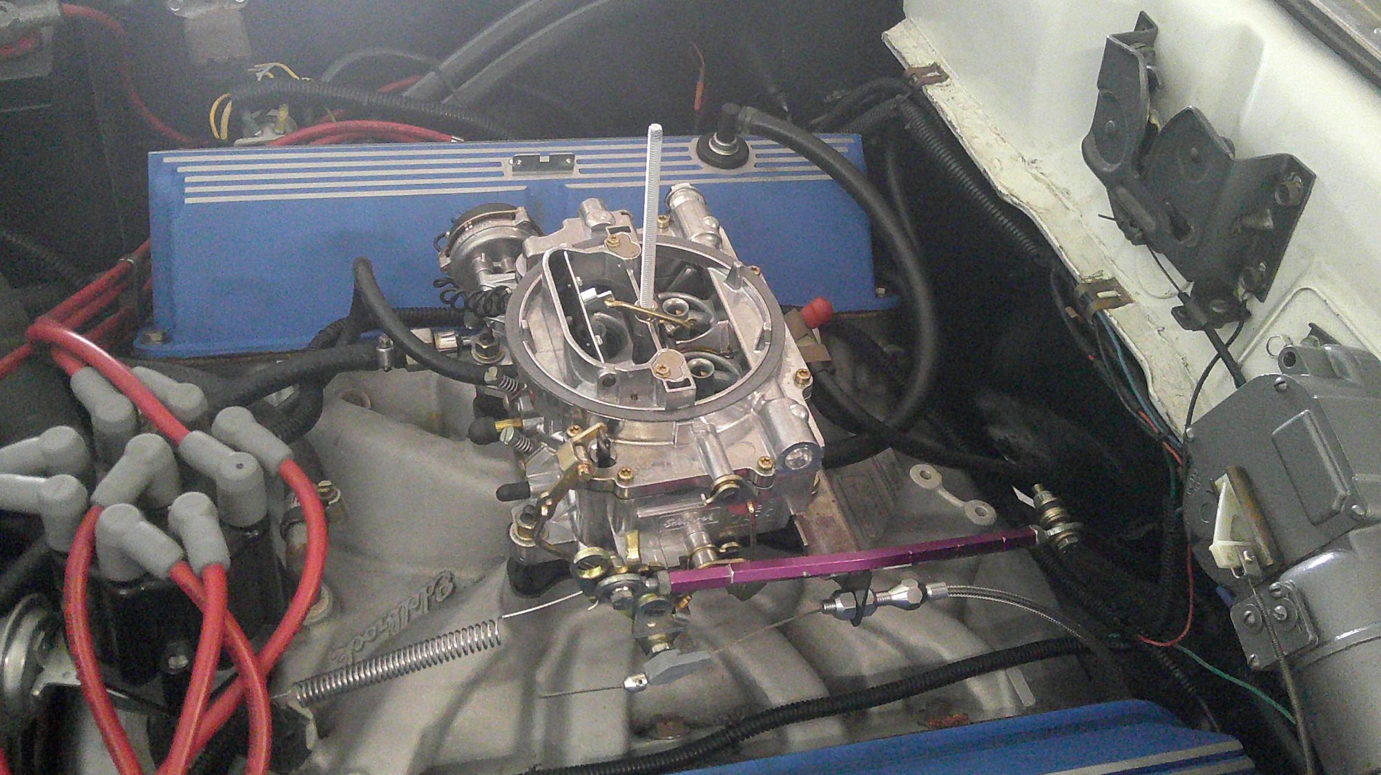 View of the carburetor and intake manifold with blue valve covers.