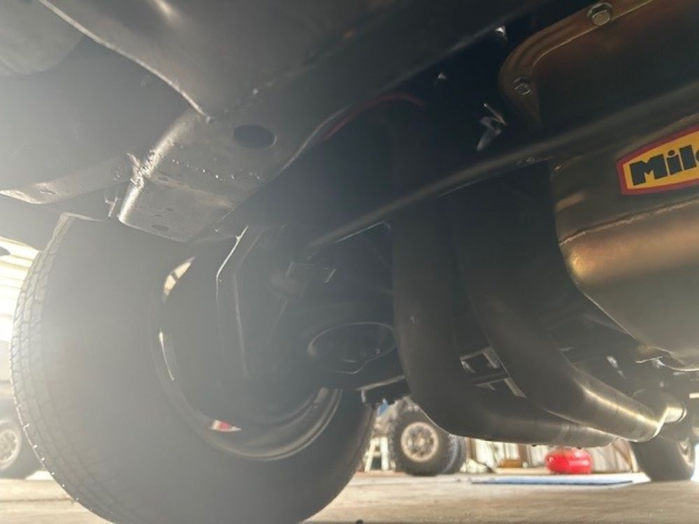 Underbody view showing chassis, suspension components, and exhaust headers.