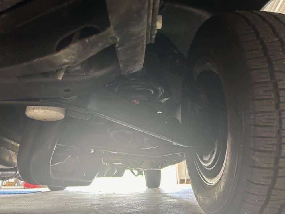 Underbody view showing front suspension components and inner tire sidewall.
