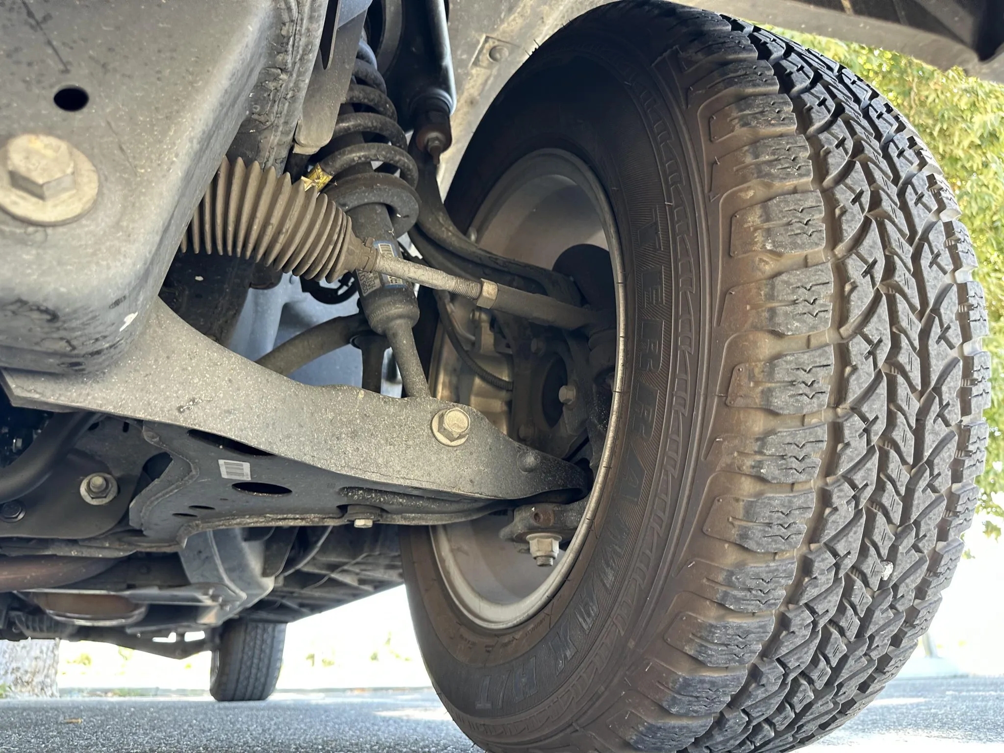 Front suspension including coil spring, control arm, and tire.