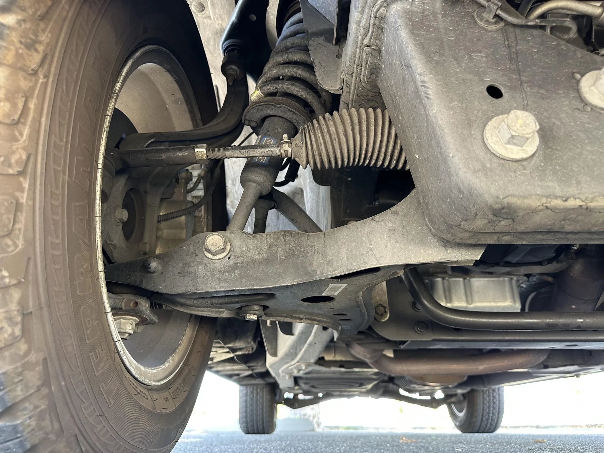 View of front suspension components, control arm, and coil spring.