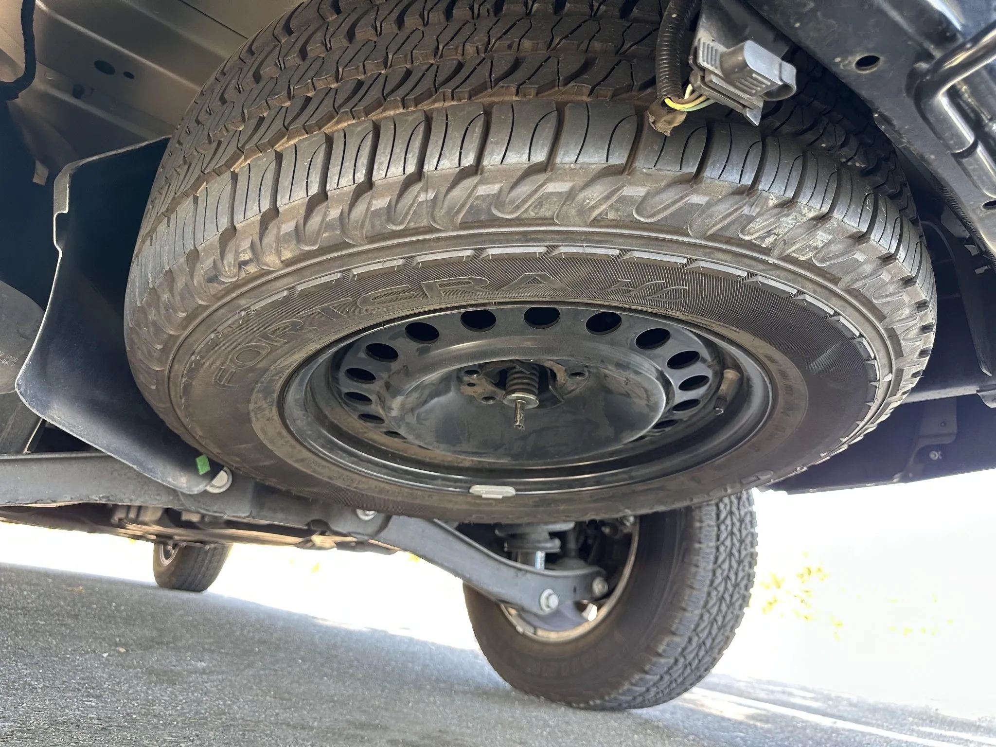 View of the undercarriage with mounted spare tire and suspension components.