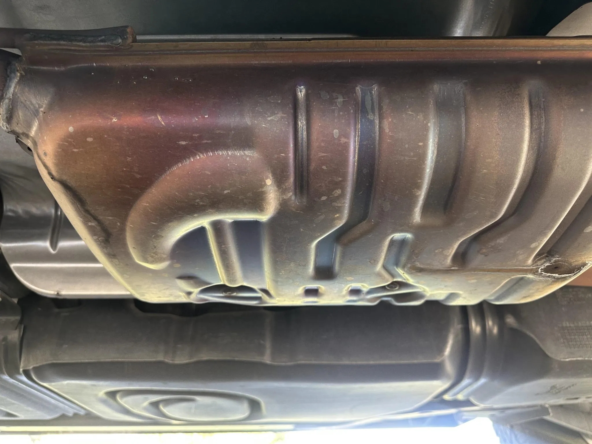 Mid-section view of the exhaust system and fuel tank from underneath.