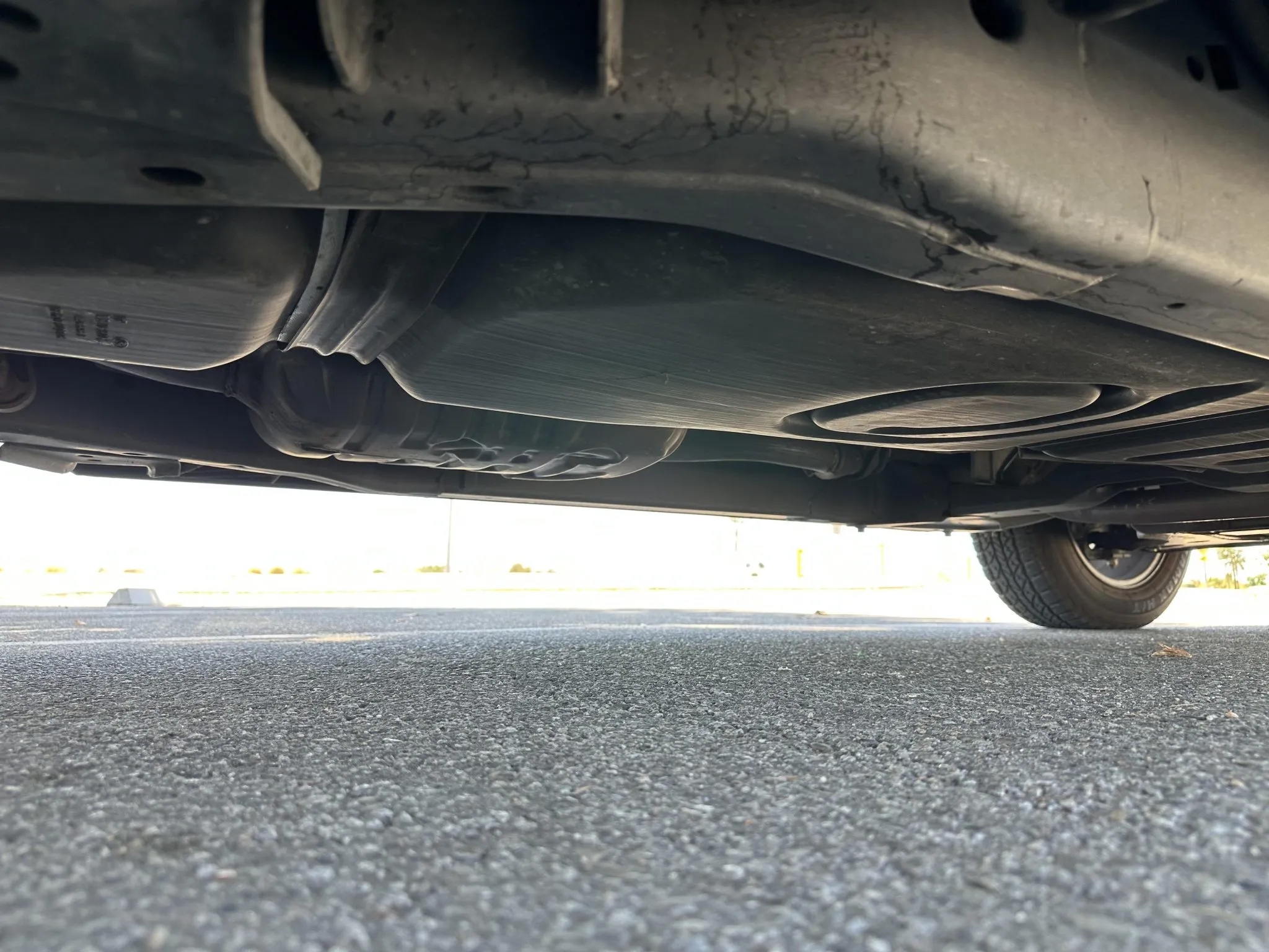 View of the chassis frame, fuel tank, and muffler from underneath.