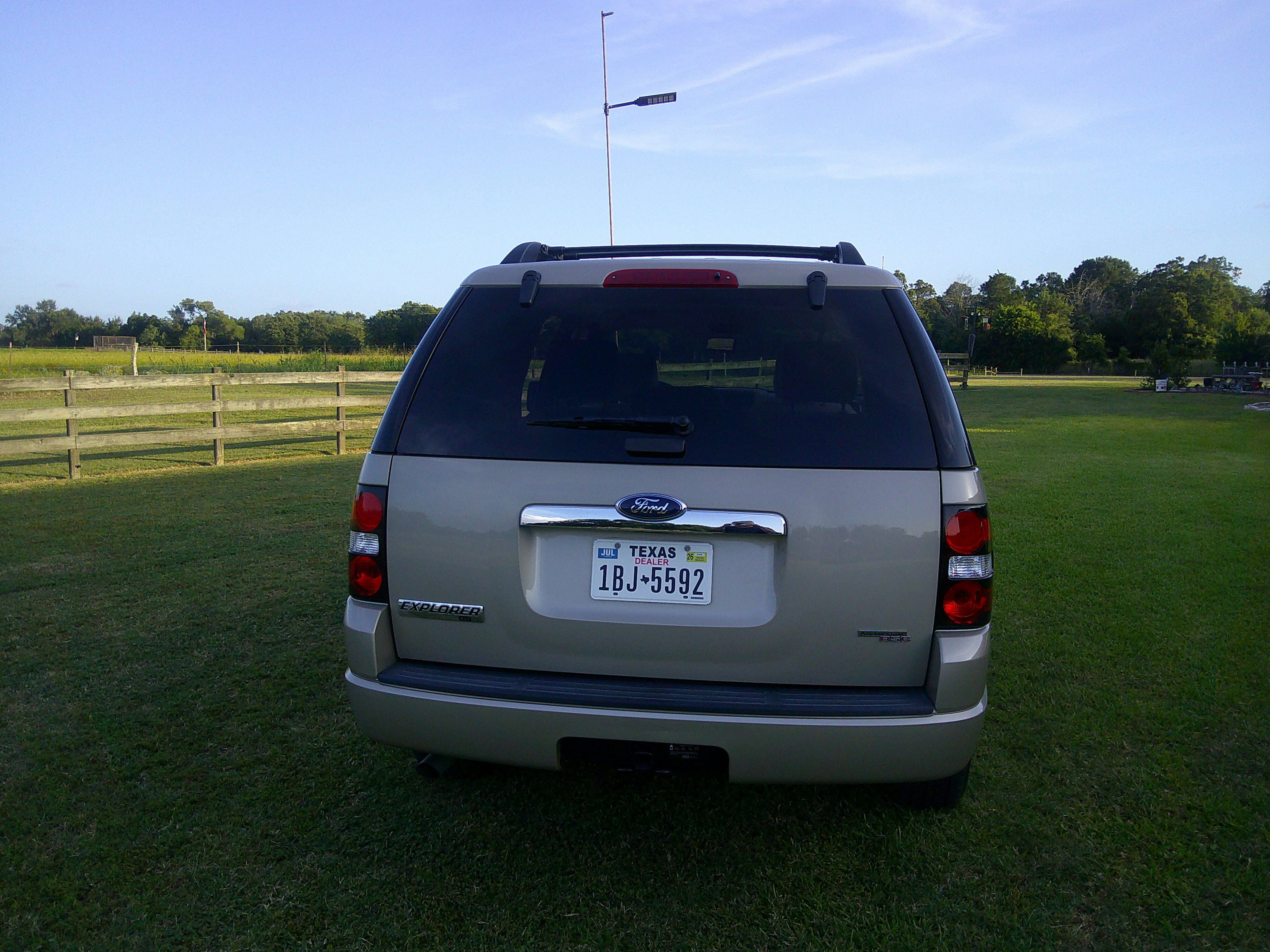 Rear view of a gold Ford Explorer with Texas dealer plates