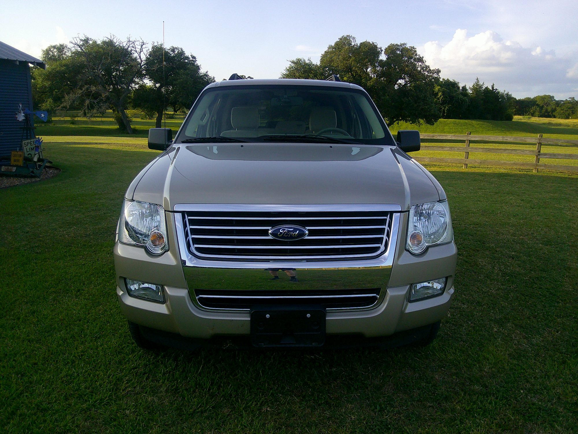 Front view of a tan Ford Explorer parked on grass.