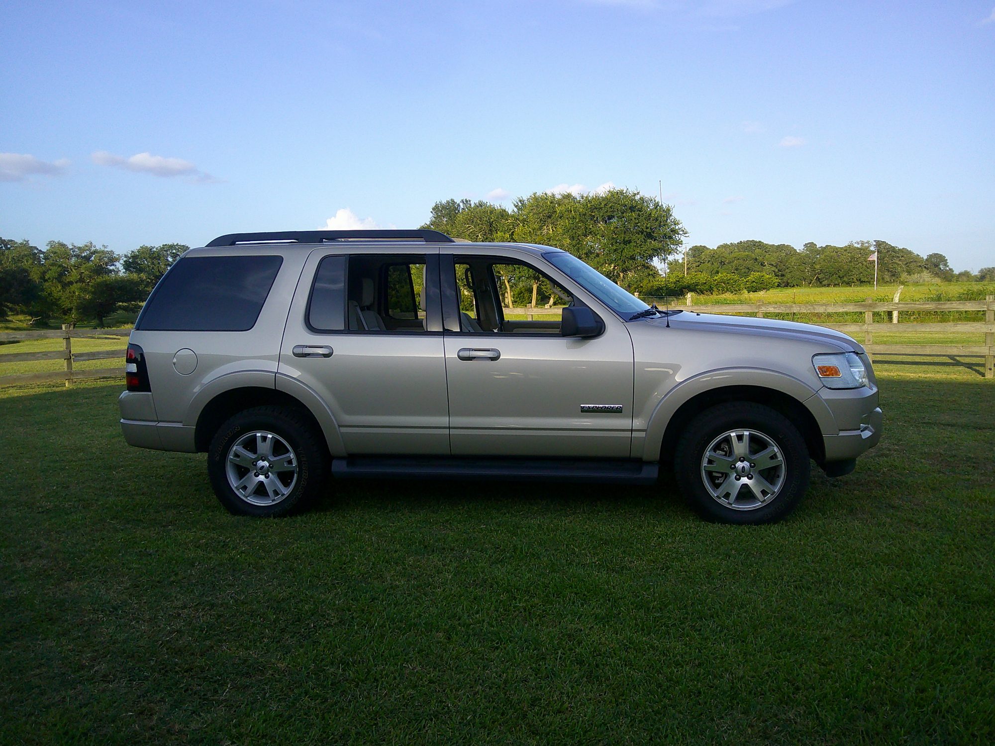 Passenger side profile of a champagne gold Ford Explorer.