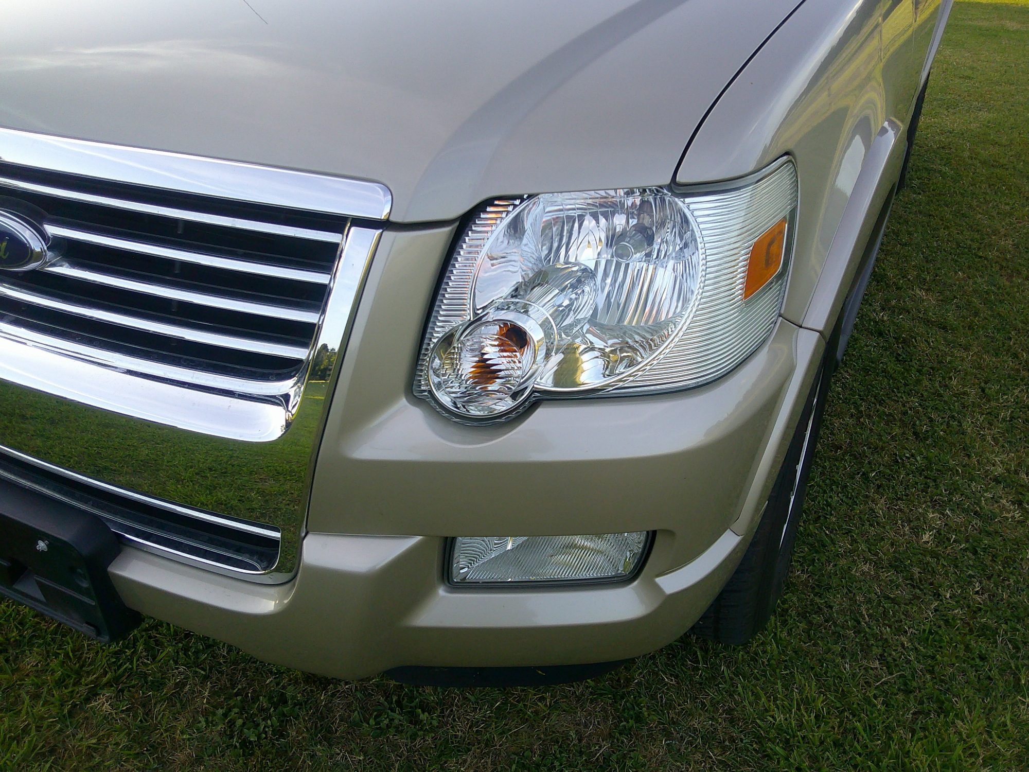 Close-up of the front driver-side headlight and chrome grille.