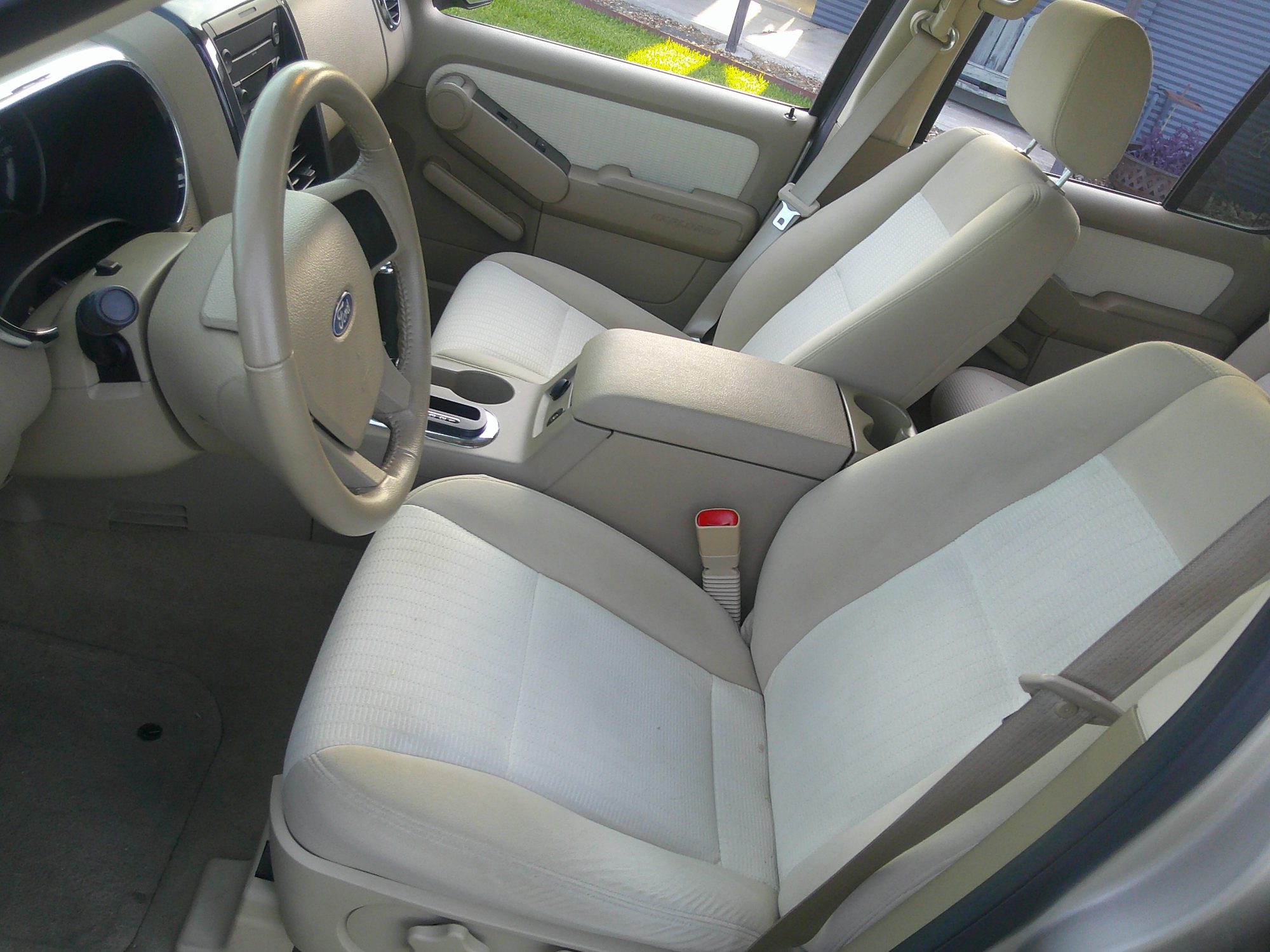 Front cabin interior showing beige cloth seats, steering wheel, and center console.