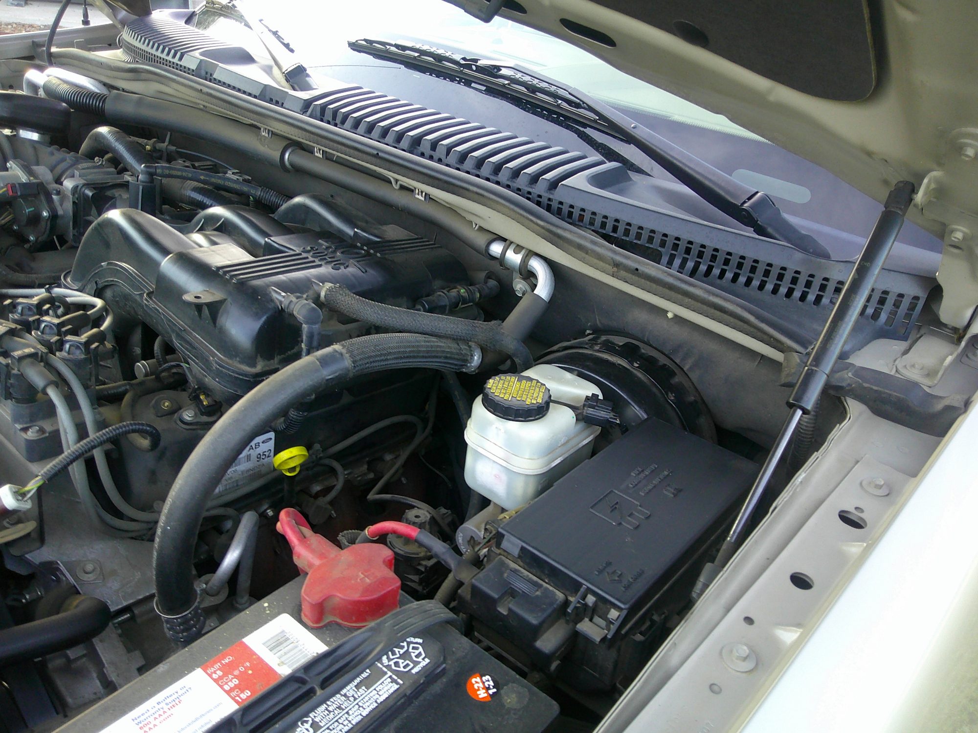 Engine bay view showing battery, fuse box, and brake fluid reservoir.