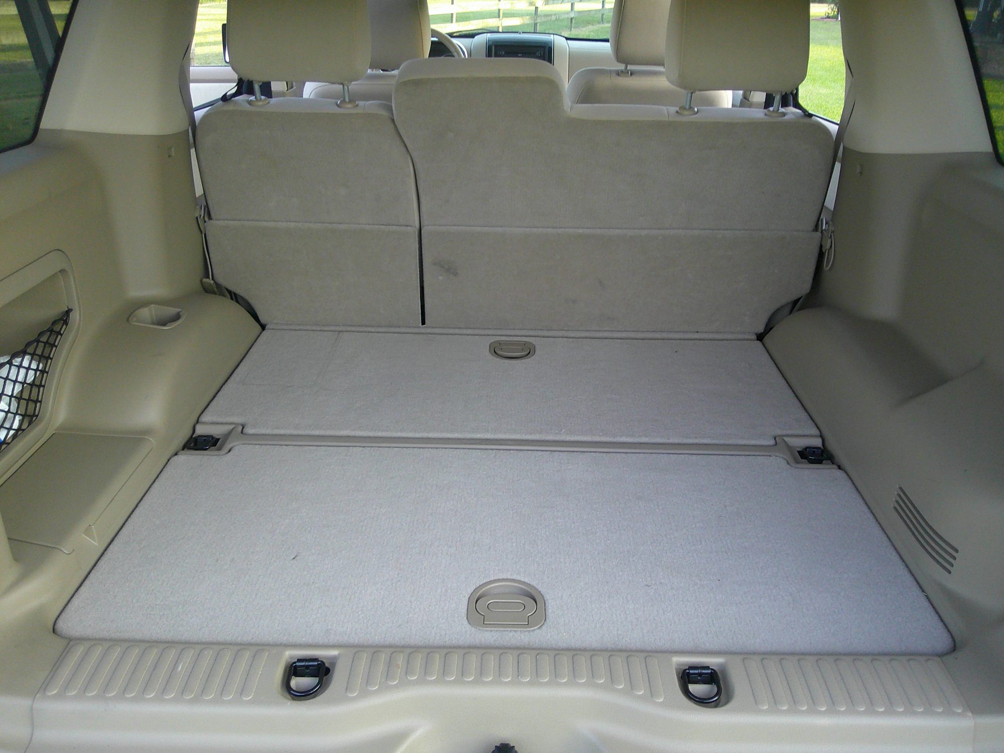 Rear cargo area with flat folding seats and tan carpeting.