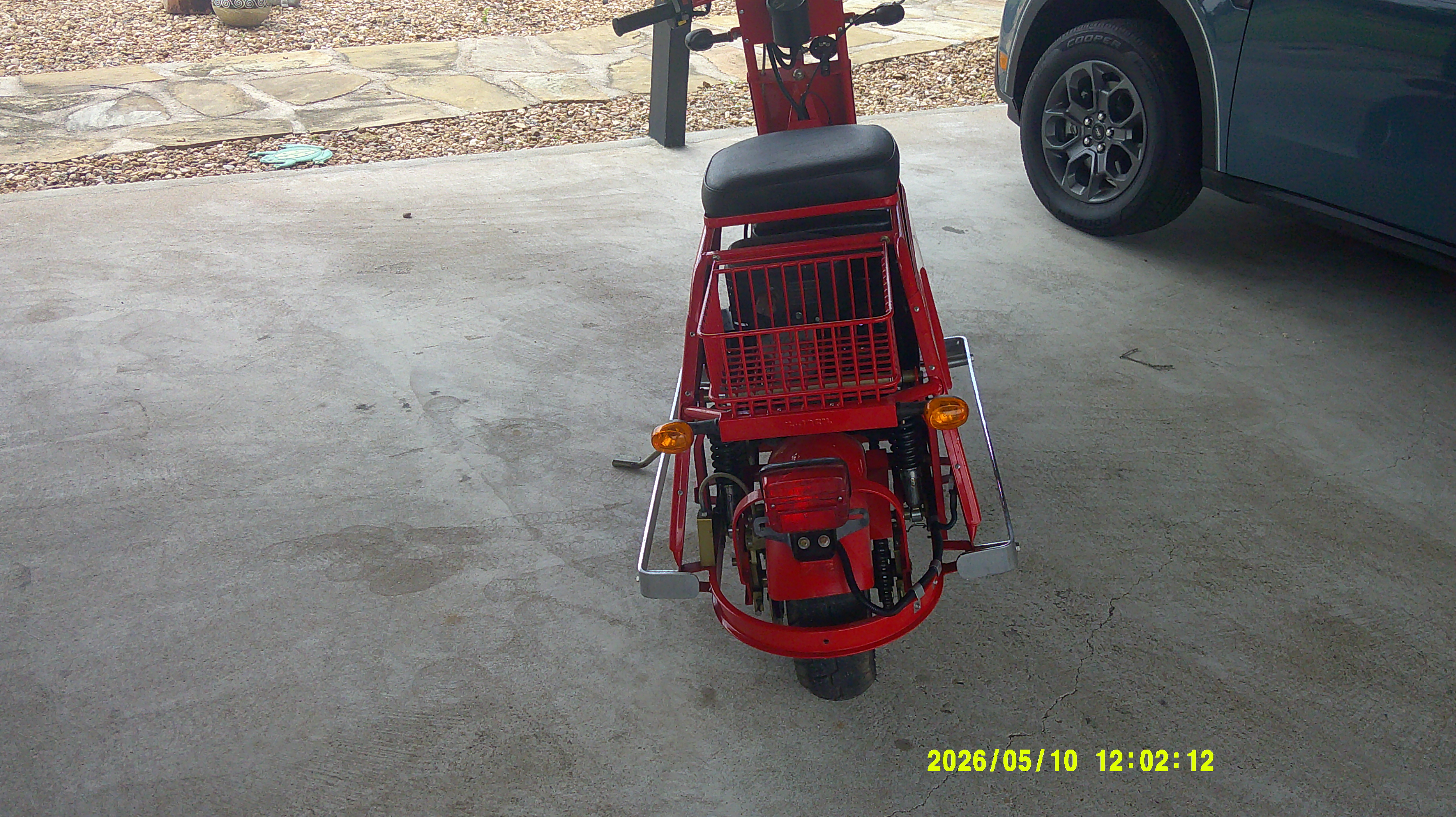 Rear view of a red vintage scooter with a wire luggage basket.