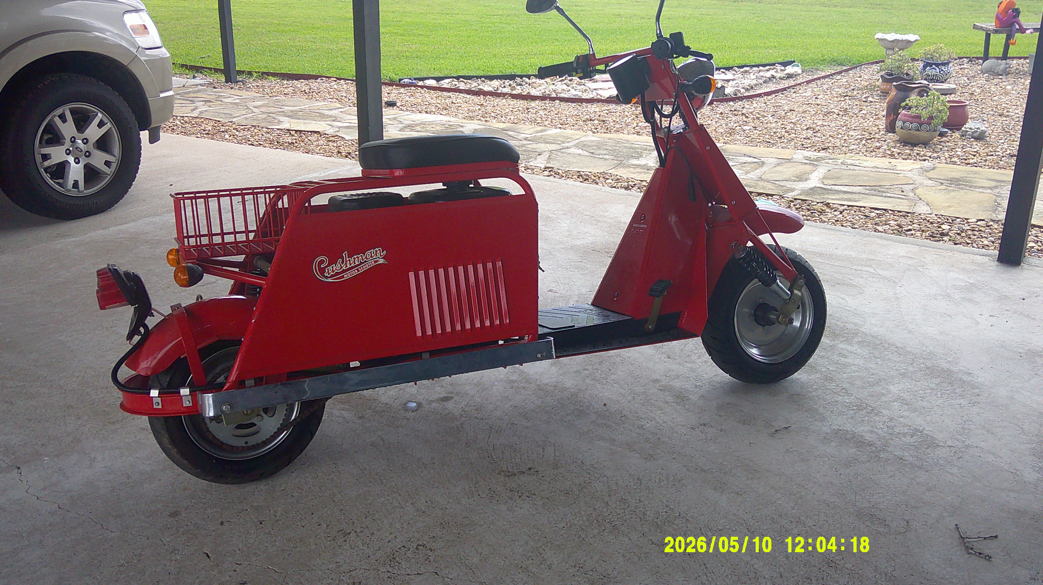 Profile view of a red Cushman motor scooter with rear basket.