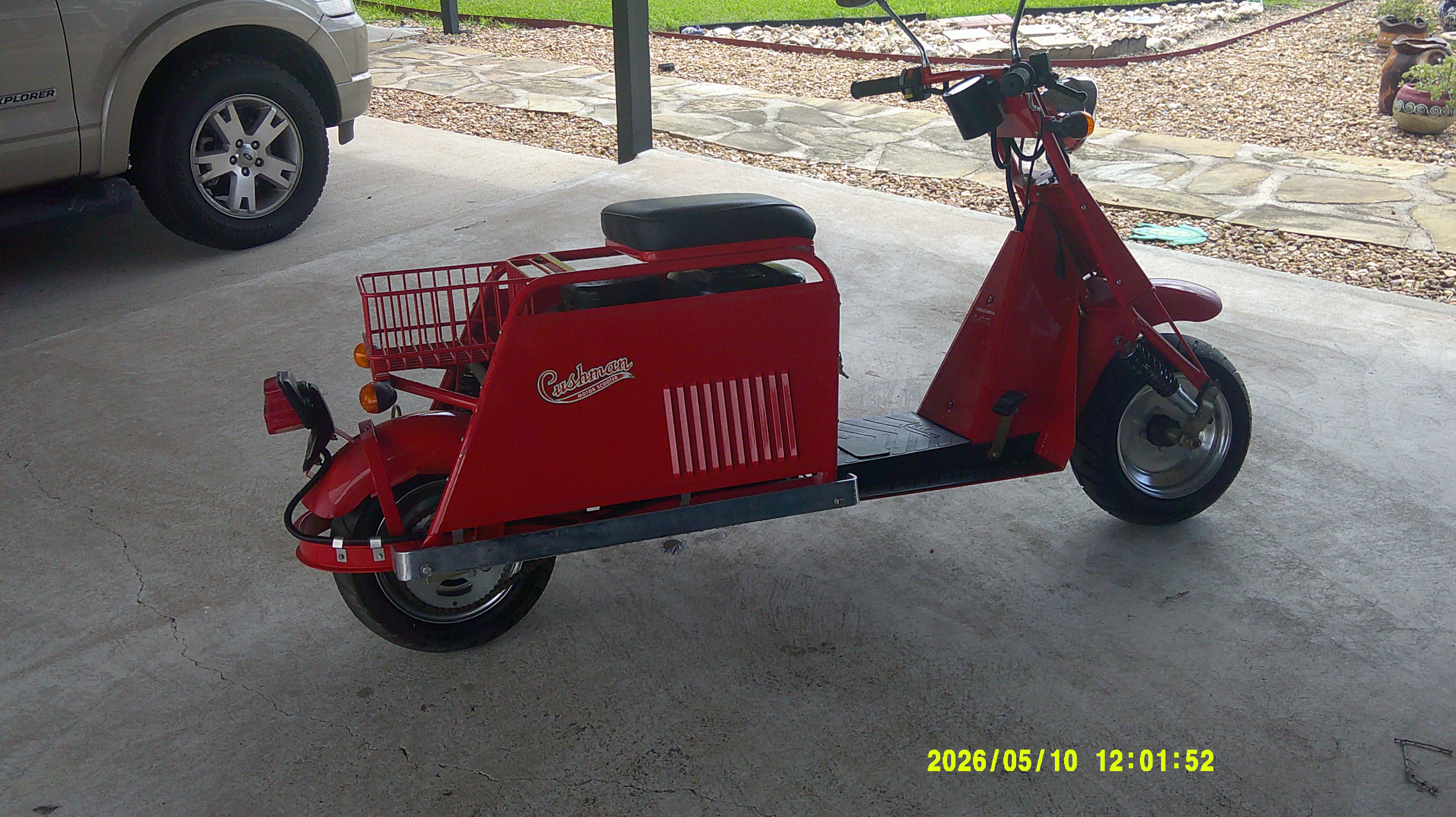 Rear three-quarter view of a red Cushman motor scooter with cargo basket.