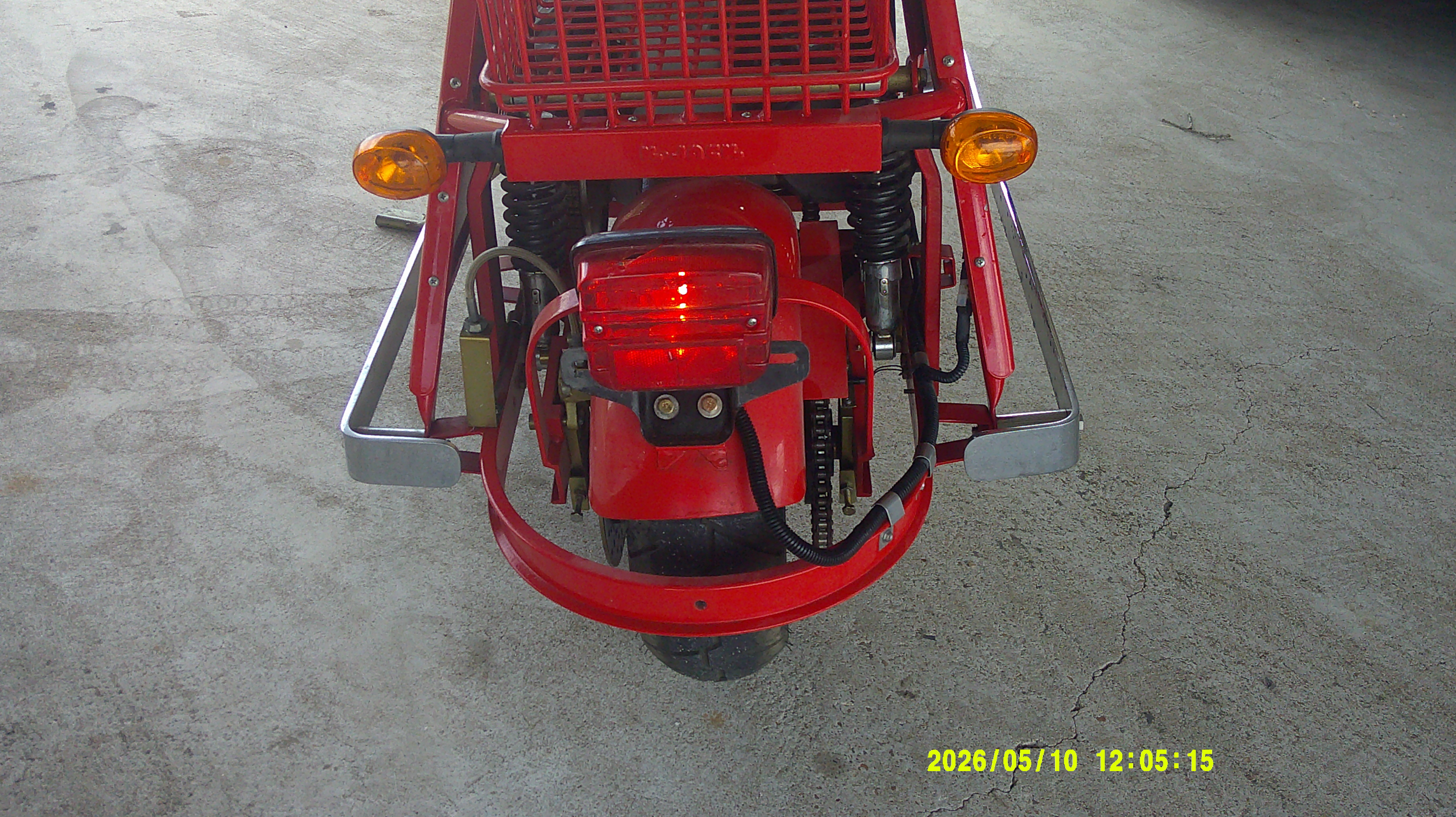 Rear view of red scooter with tail light, turn signals, and storage basket.