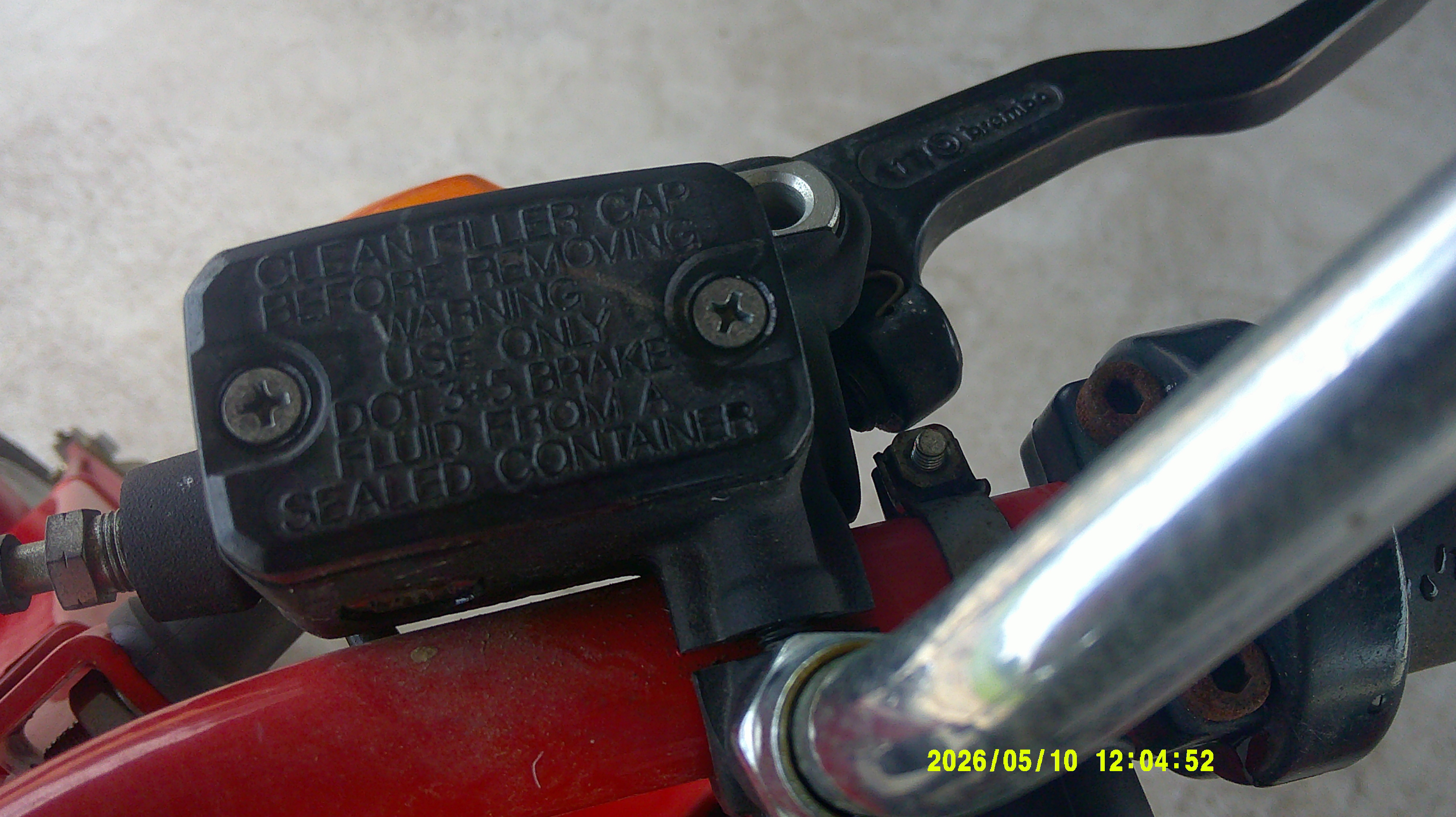 Brake fluid master cylinder reservoir on handlebar with Brembo lever.