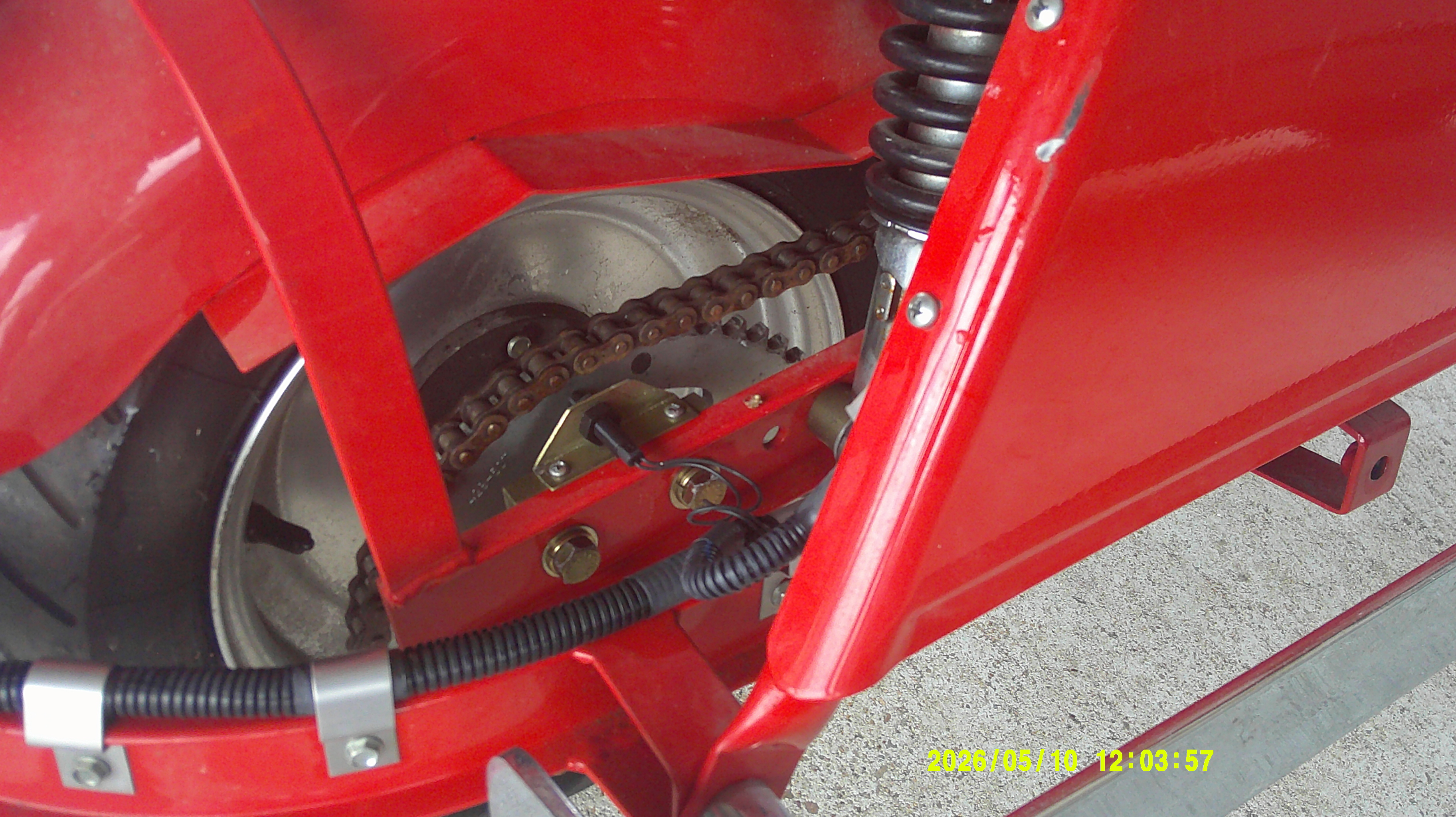 Rear drive chain, sprocket, and suspension coil assembly.