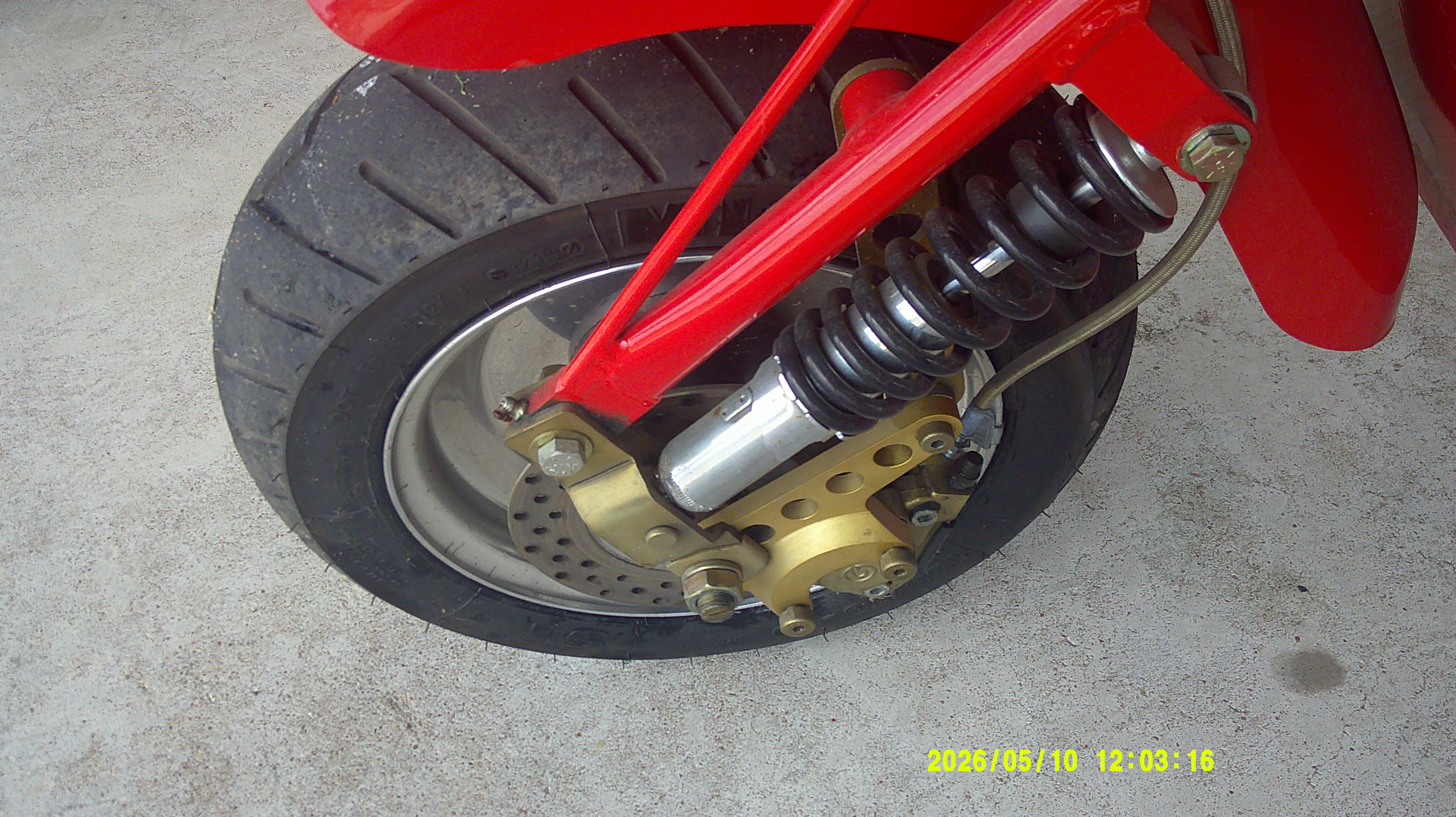 Close-up of the front wheel assembly including shock absorber and brake disc.