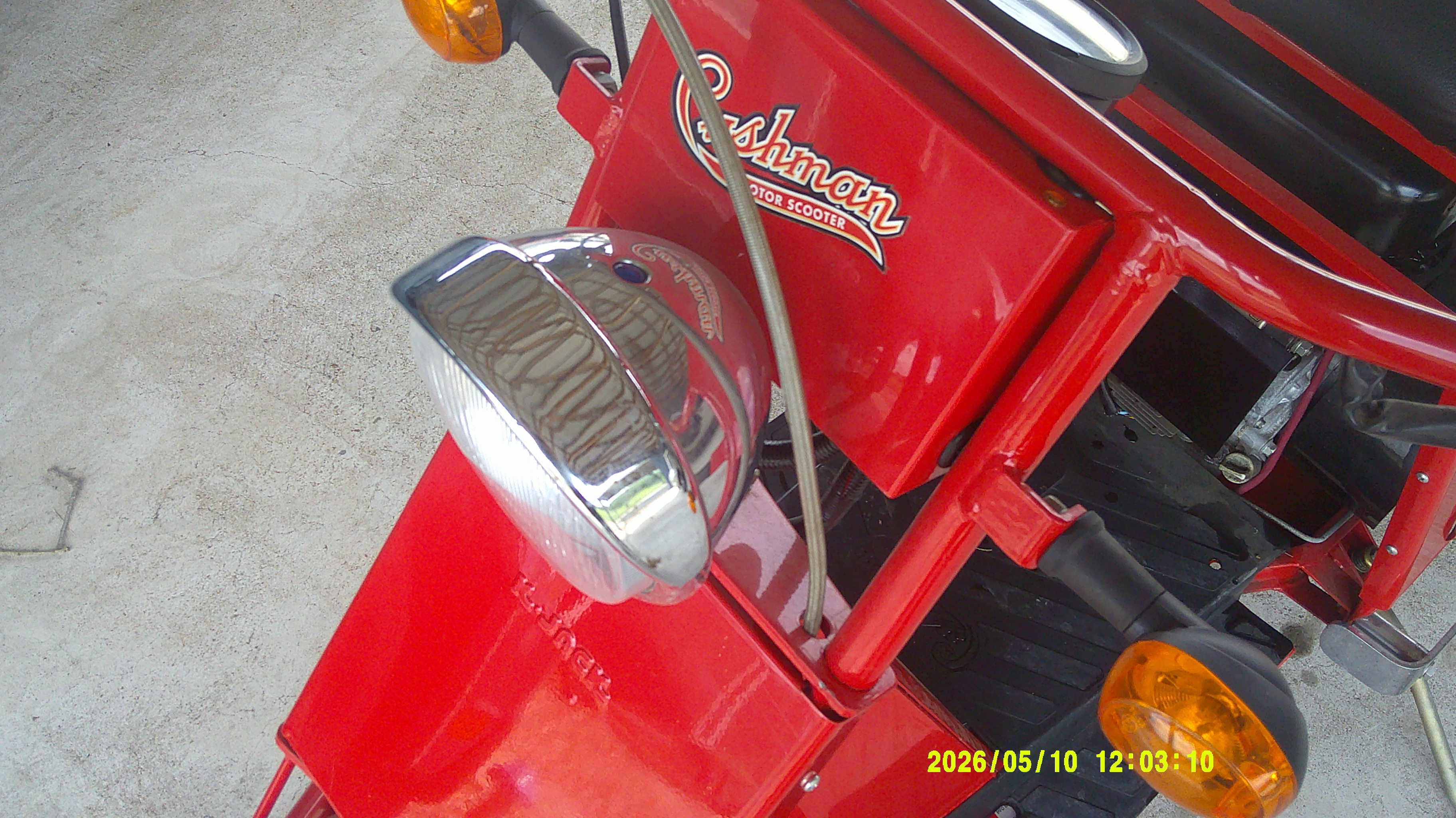 Red Cushman scooter front showing chrome headlight and logo emblem.