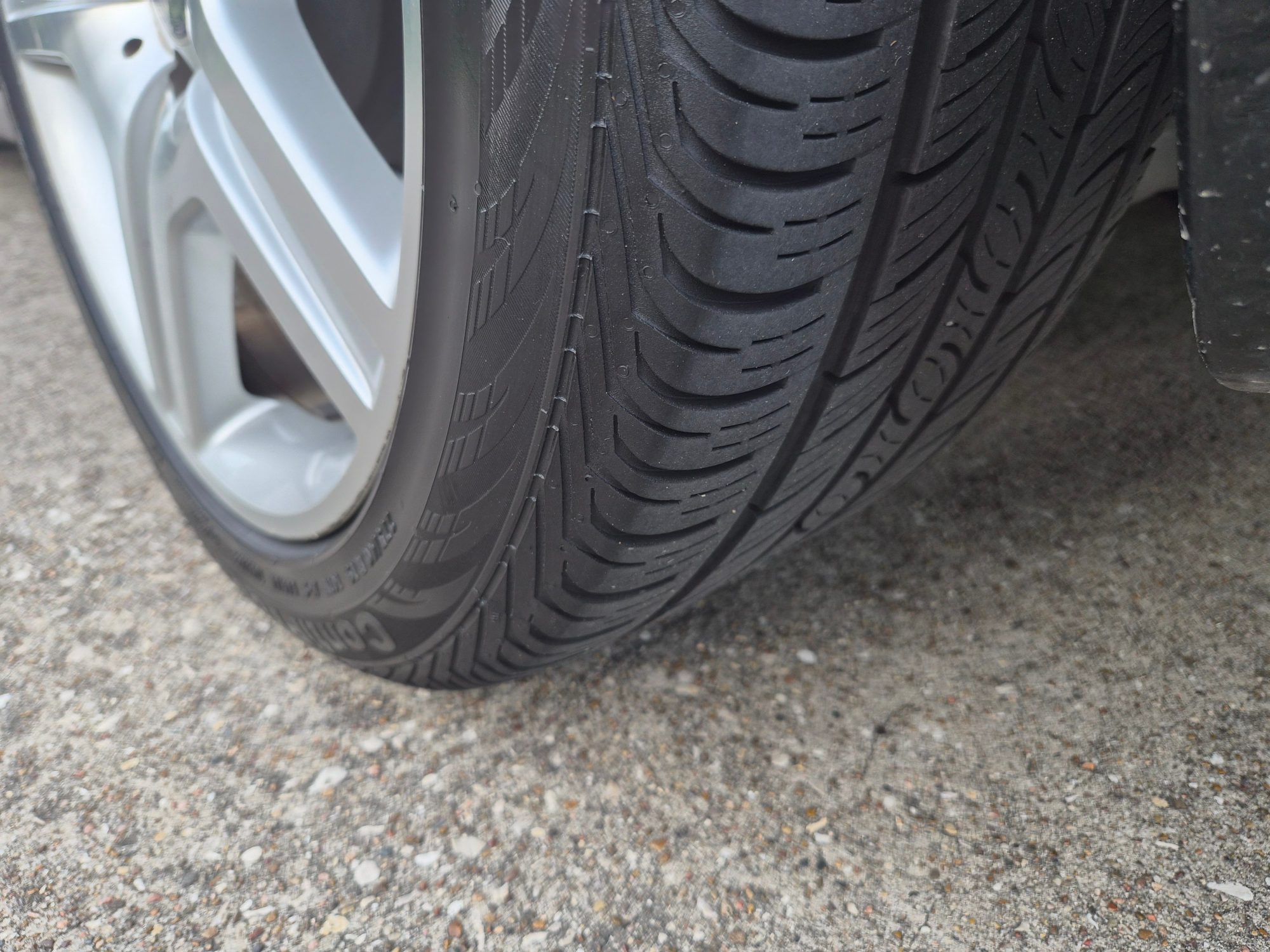 Close-up of tire tread and silver multi-spoke wheel