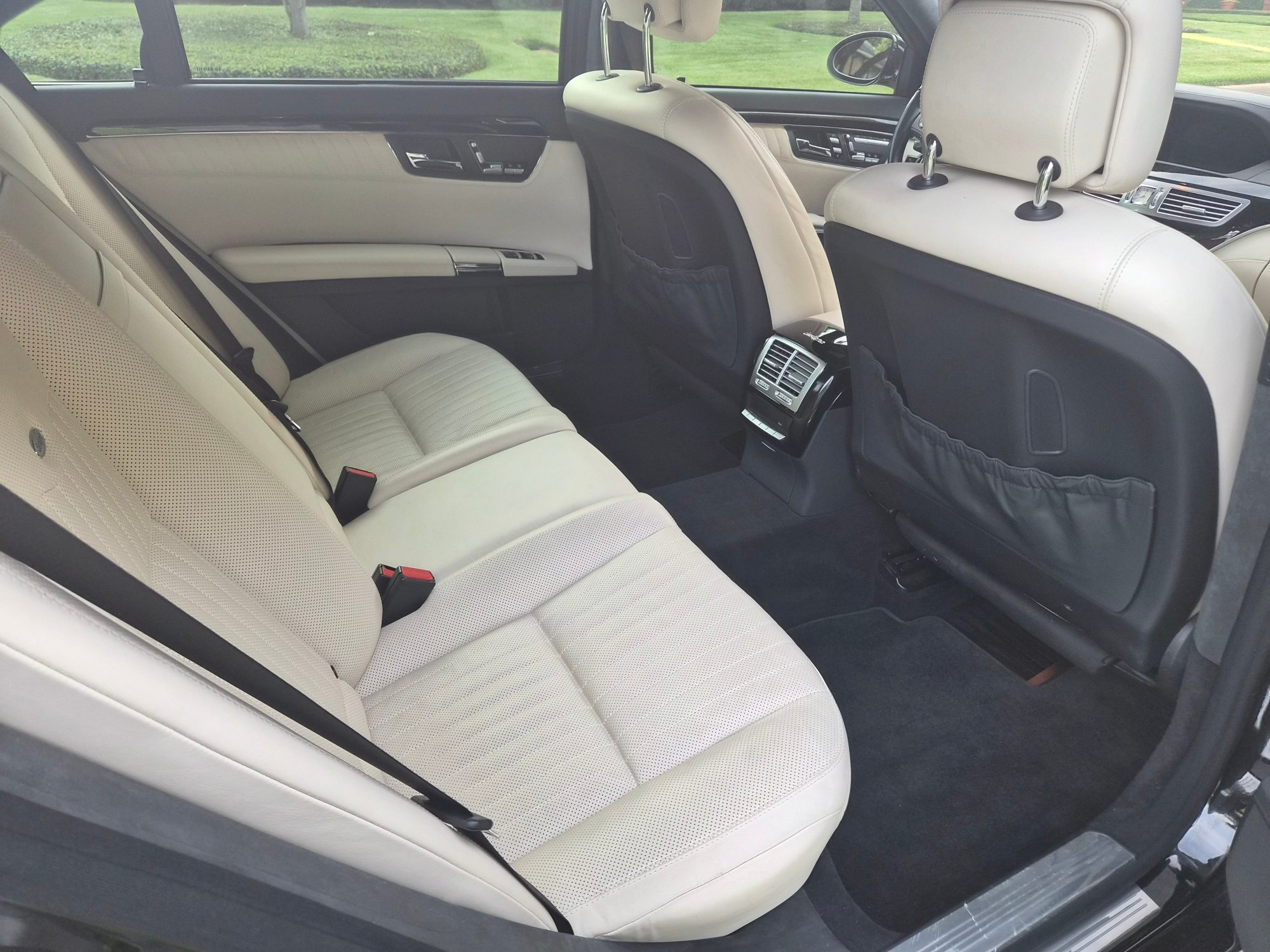 Rear passenger cabin with white leather upholstery and center console vents.