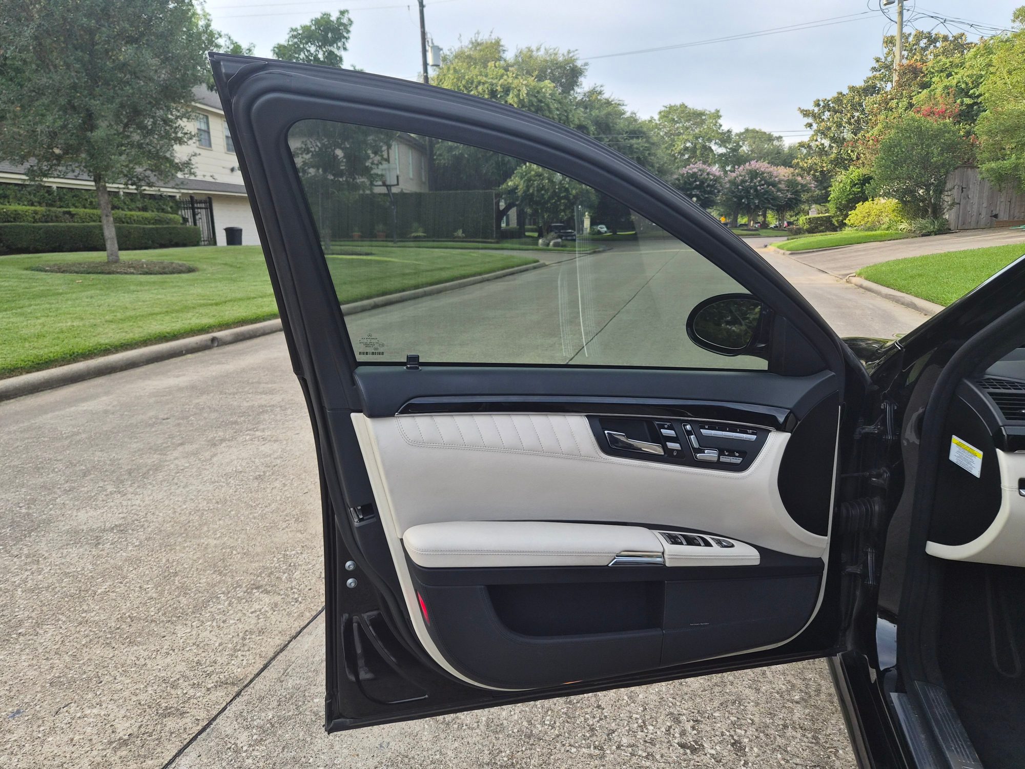 Driver side door panel with cream leather upholstery and seat controls.
