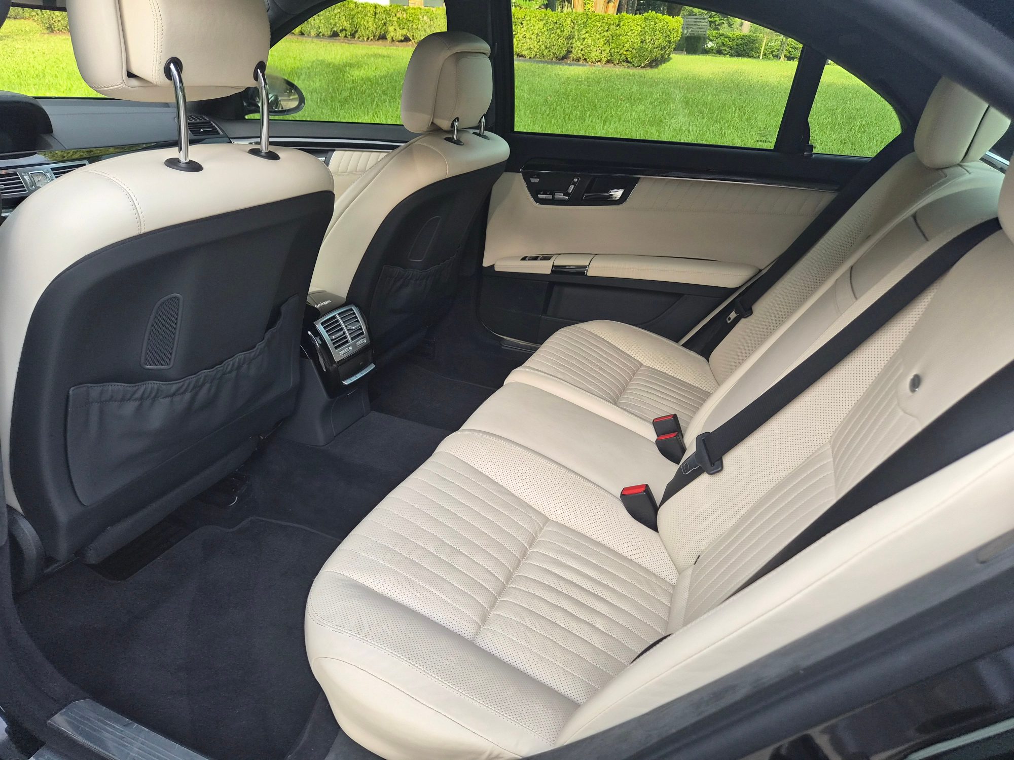 Rear passenger seating area with cream leather upholstery and dark carpeting.