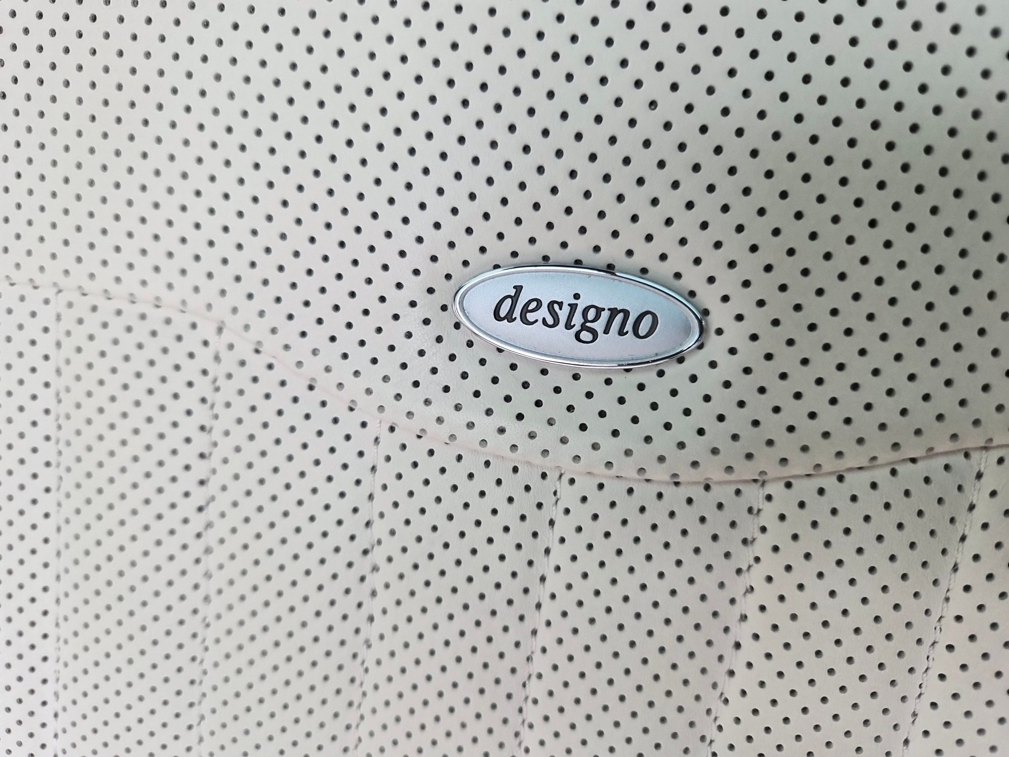 Close-up of Designo emblem on perforated leather seat upholstery.