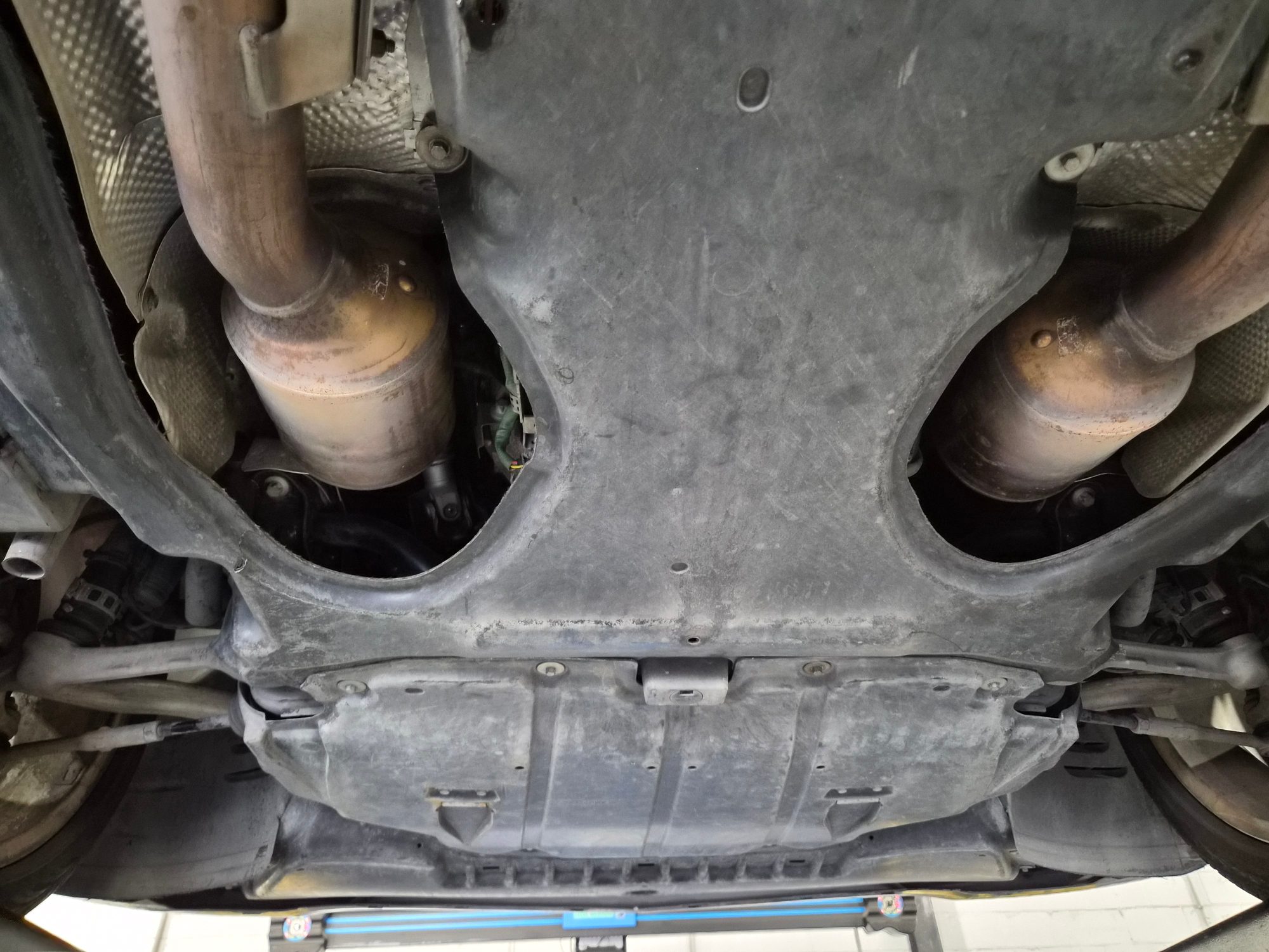 Underbody view showing exhaust pipes and protective undertray panels.