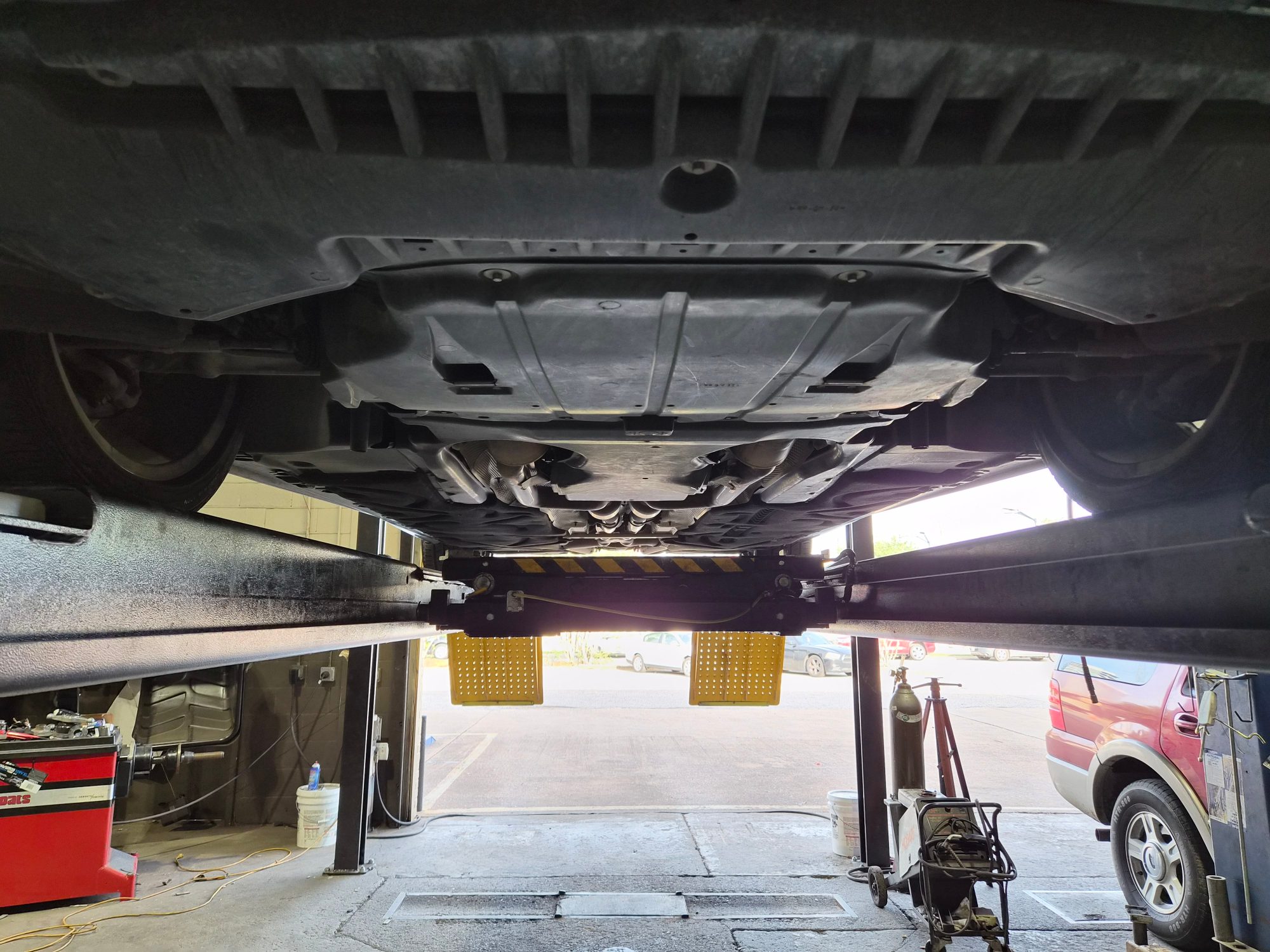 Vehicle undercarriage view showing skid plates and exhaust system on a lift.