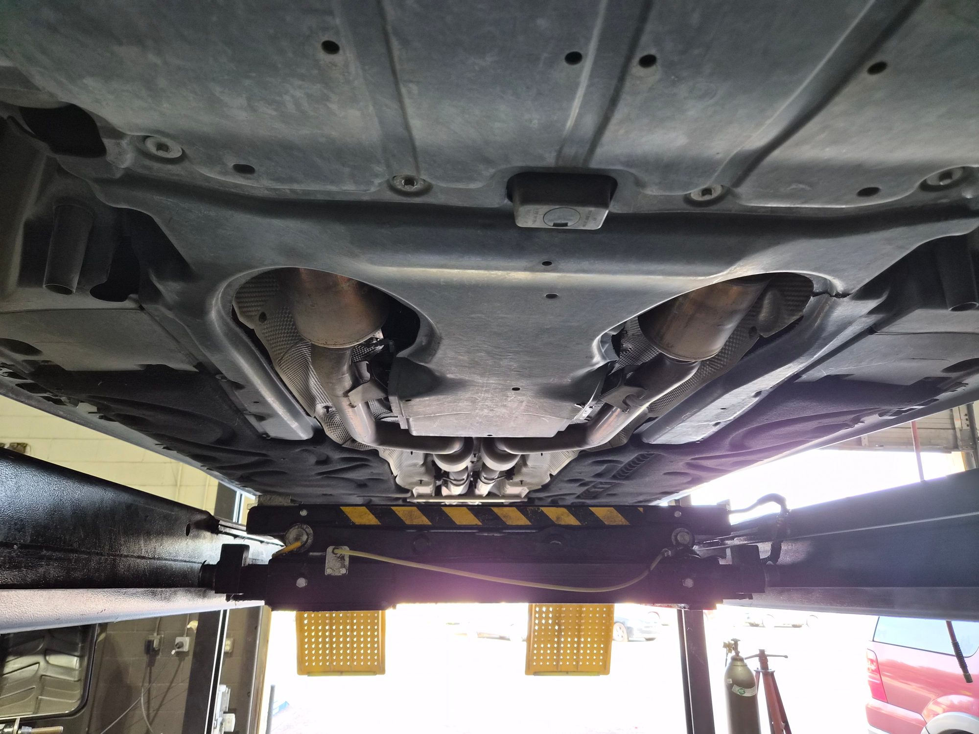 Underbody view showing chassis panels and dual exhaust system on a lift.
