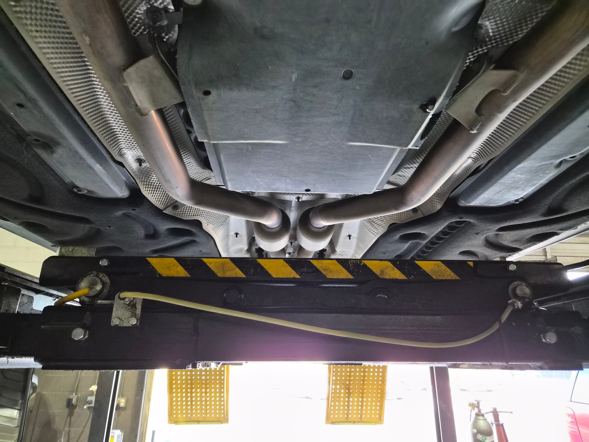 Underbody view of the vehicle chassis and exhaust system on a lift.