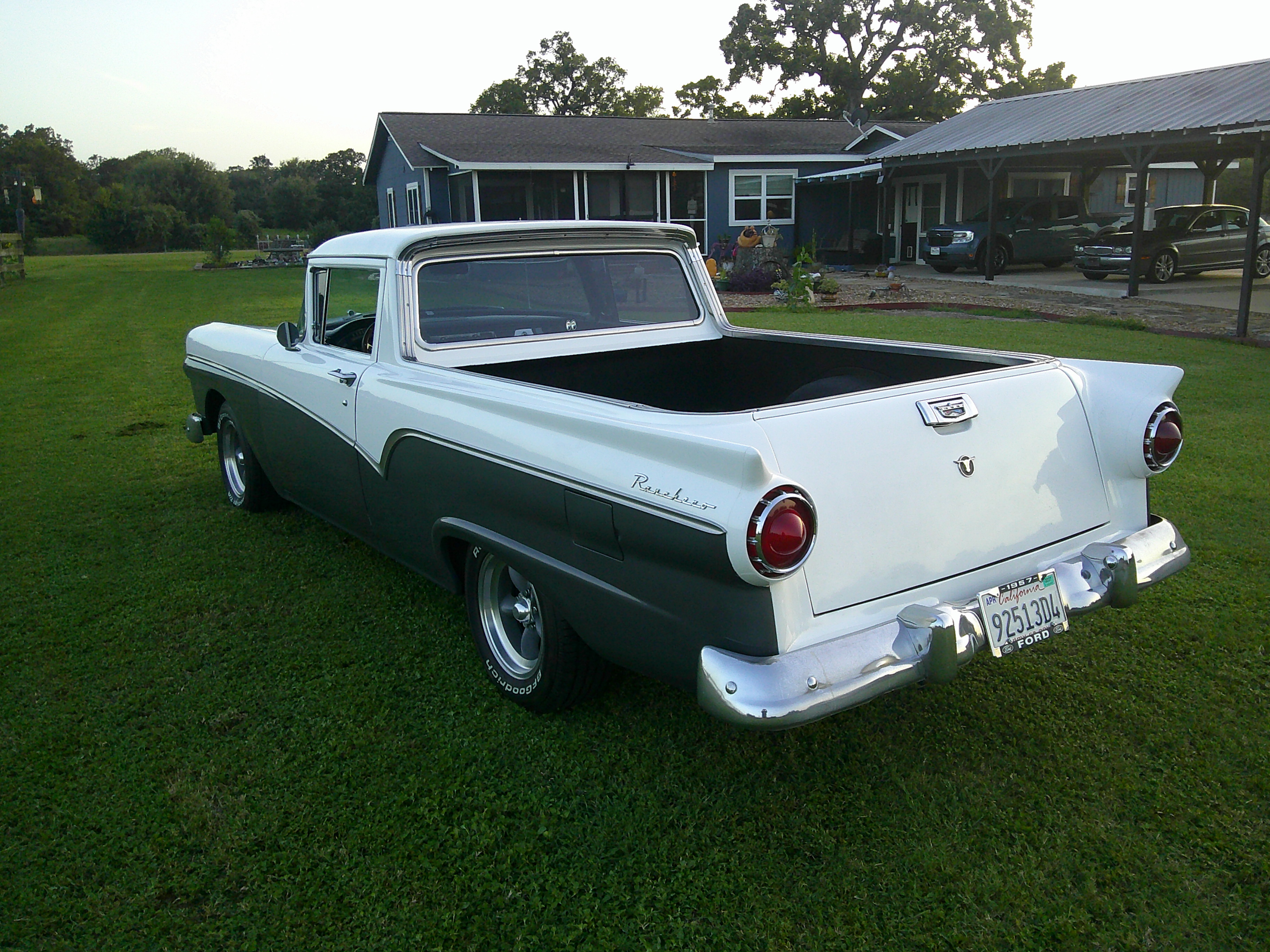 Rear three-quarter view of a two-tone 1957 Ford Ranchero in a field.