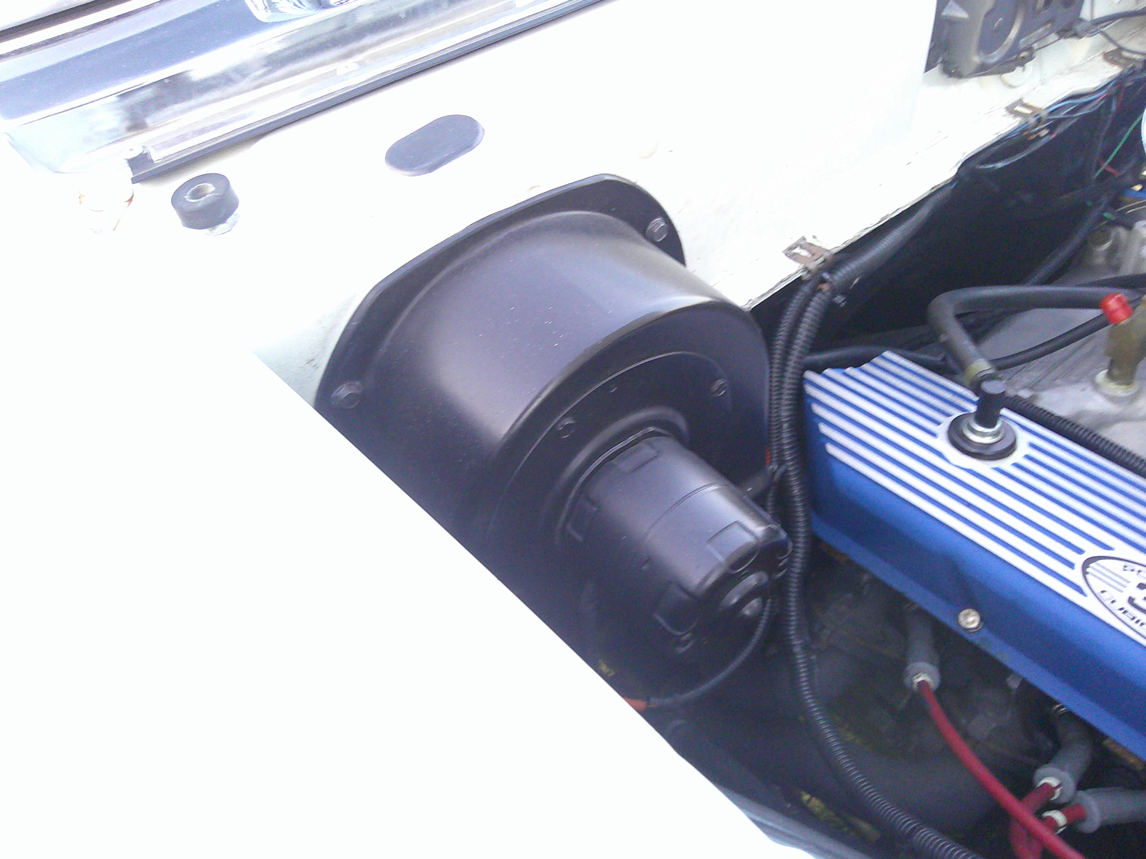 Blower motor and heater housing in the engine bay adjacent to the valve cover.