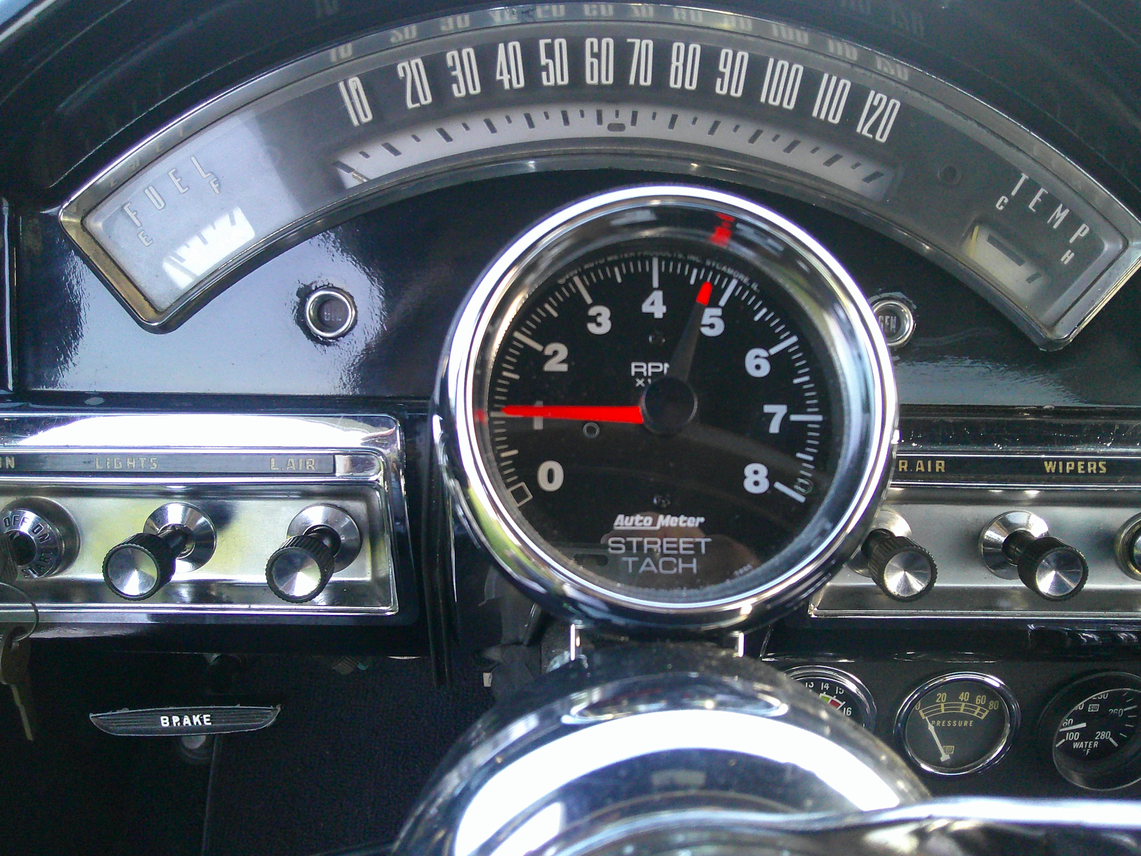 Dashboard instrument panel featuring an aftermarket tachometer and original gauges.