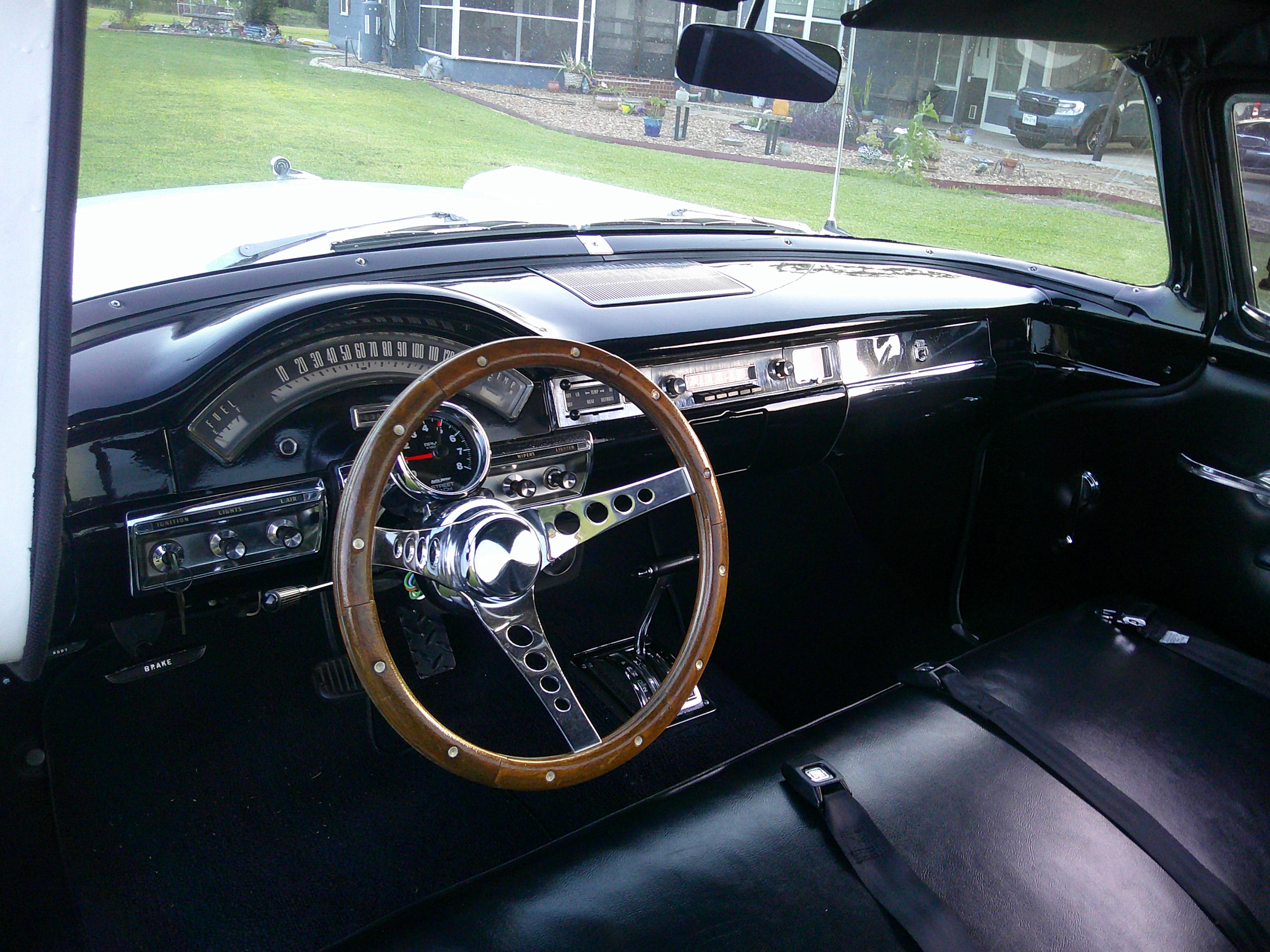 Black dashboard with wood-rimmed steering wheel and bench seat
