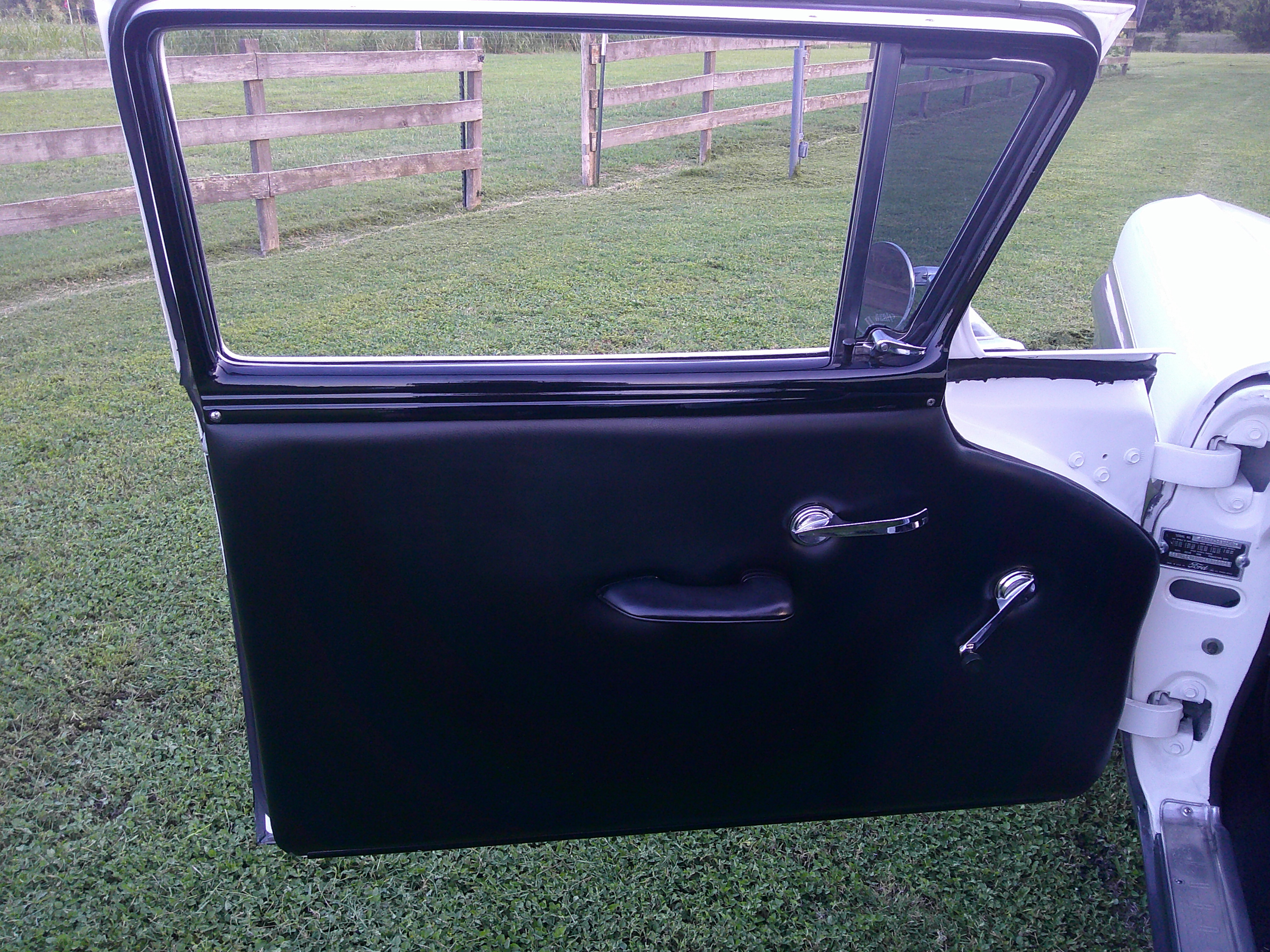 Interior side of car door with black upholstery and chrome hardware.