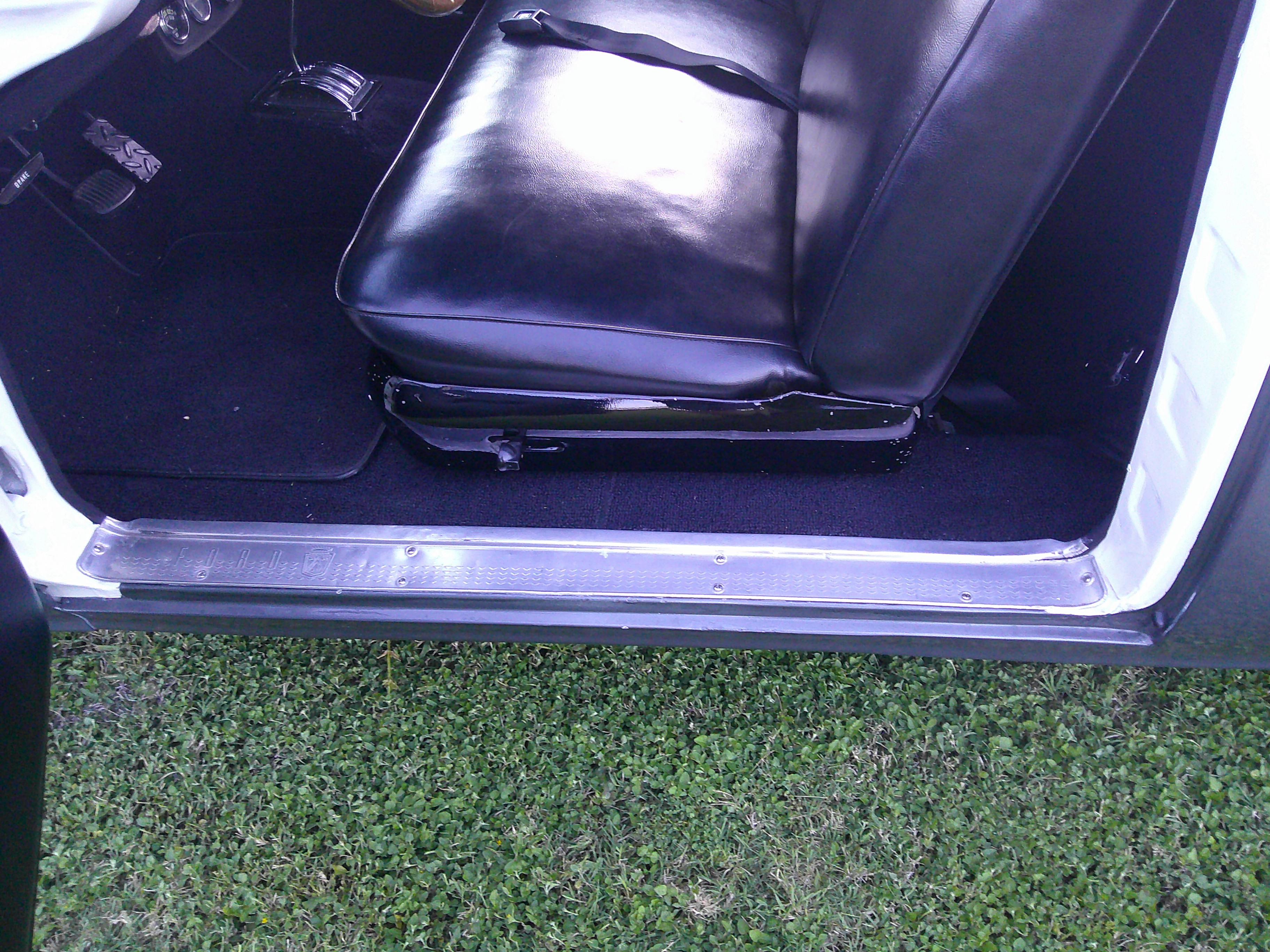 Driver side interior showing seat, door sill, and pedal assembly.