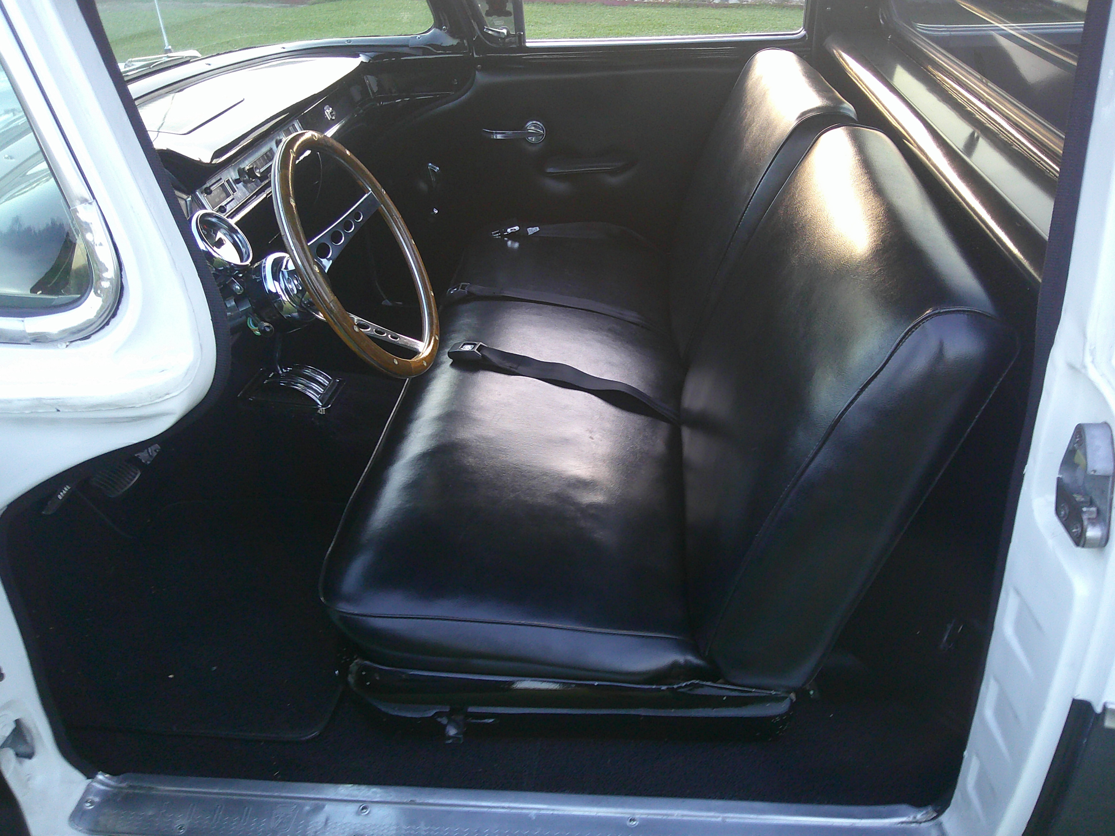 Black vinyl bench seat and interior cabin with wood-rimmed steering wheel.