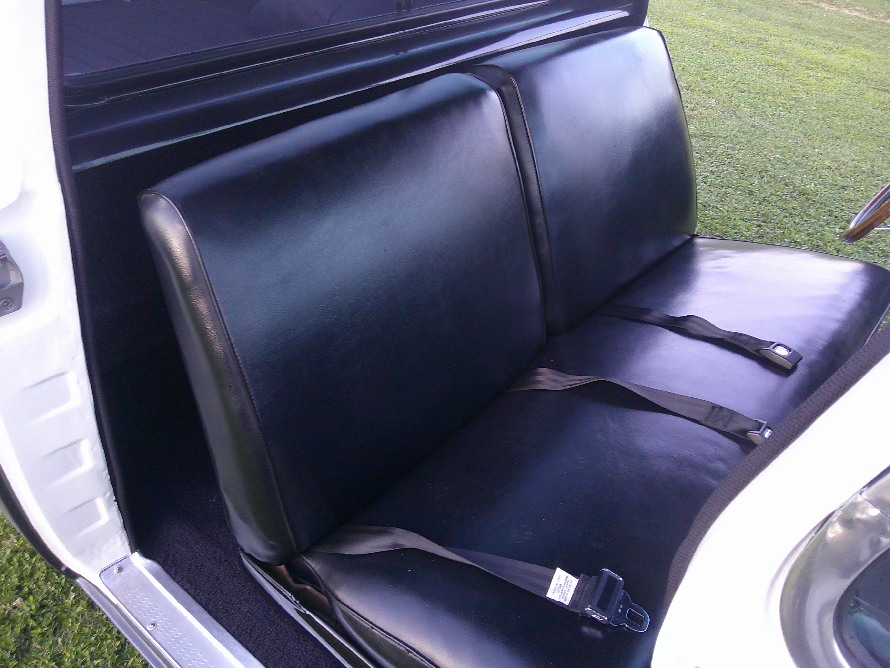 Black vinyl bench seat and lap belts inside a classic truck cab.