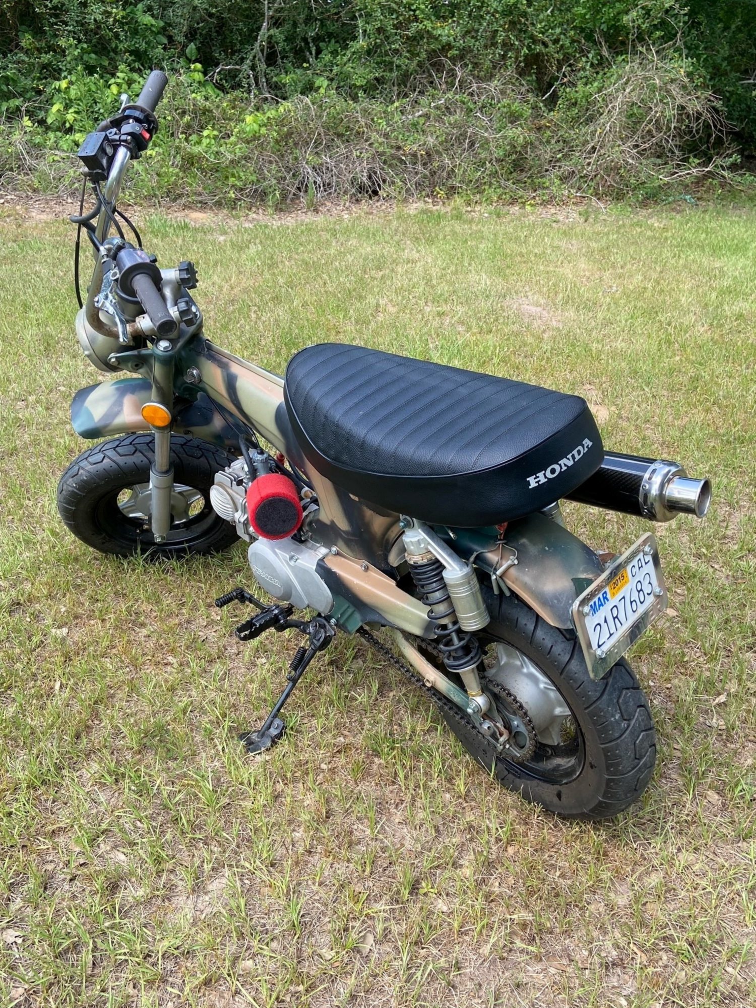 Rear three-quarter view of a camouflage Honda mini bike with custom exhaust.
