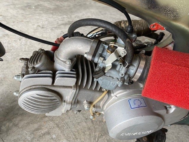 Close-up of a small single-cylinder engine with carburetor and red foam air filter.