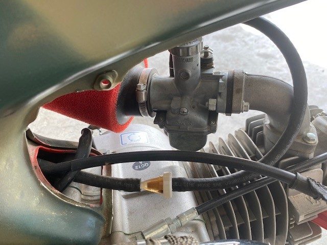Close-up of carburetor and fuel lines on a small displacement engine.