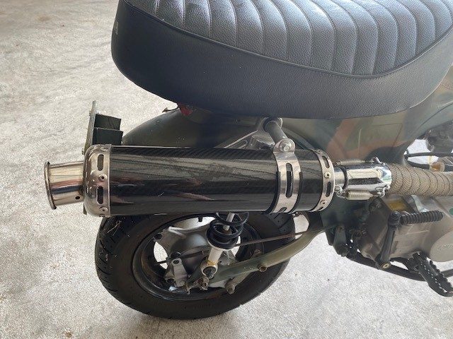 Custom carbon fiber exhaust muffler and rear wheel of a small motorcycle.