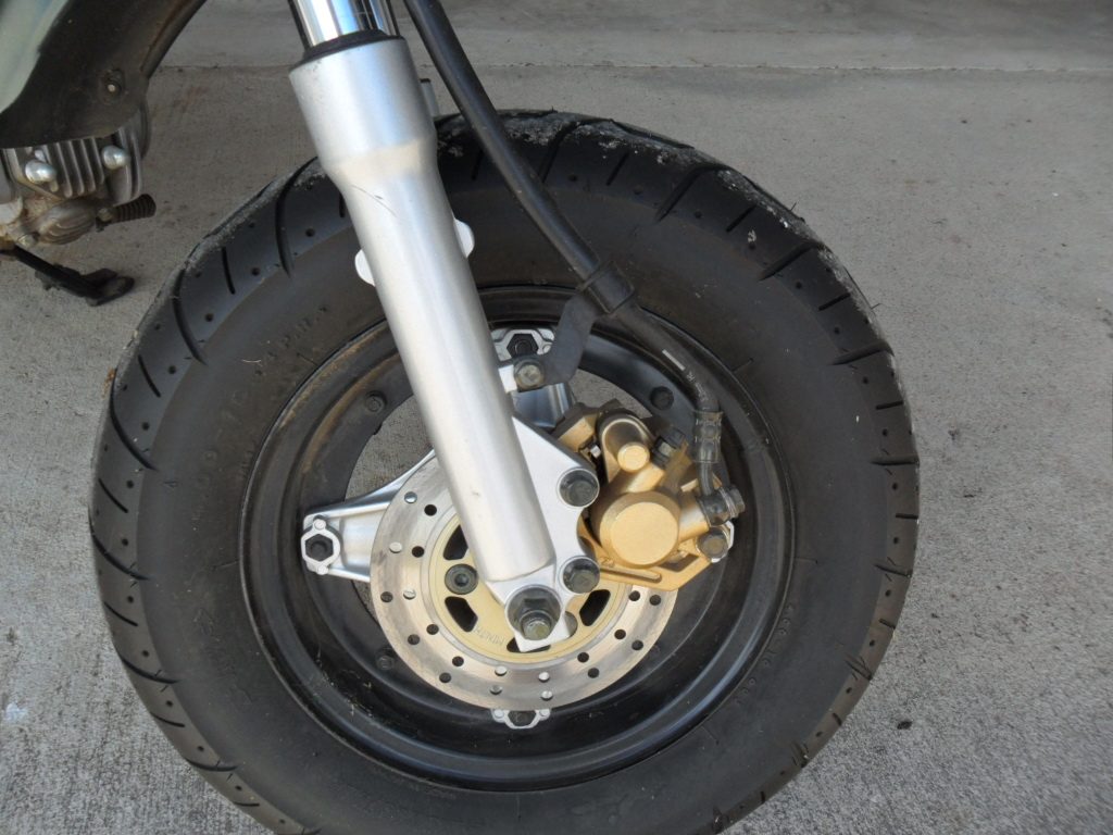 Close-up of the front wheel, brake rotor, and gold caliper.