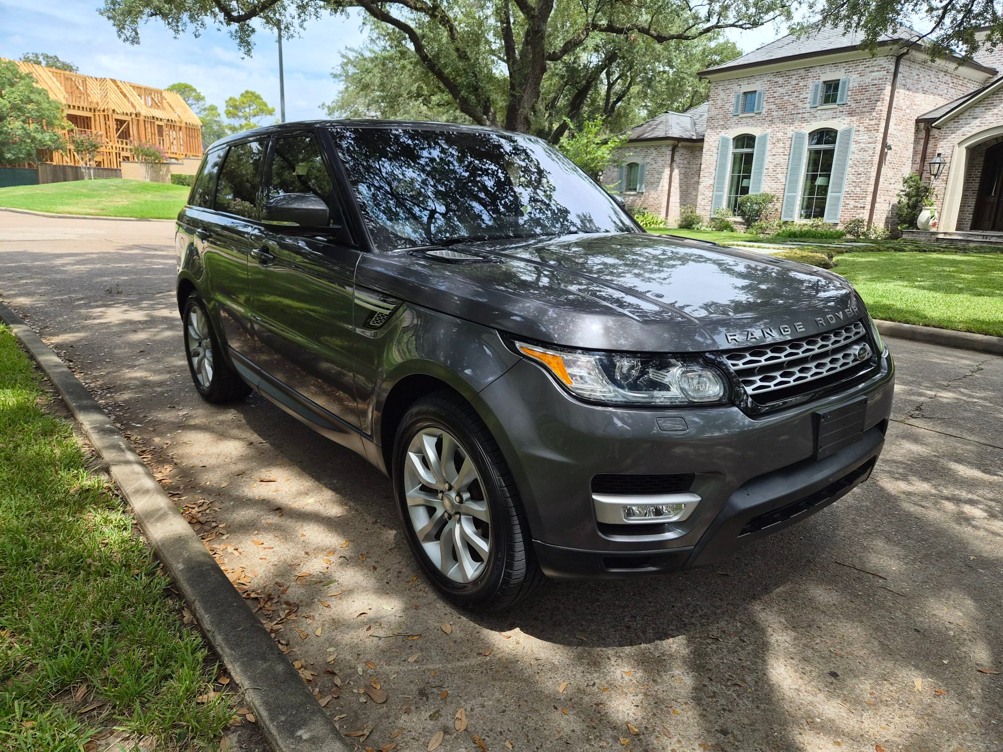Front three-quarter view of a grey Range Rover Sport parked on a driveway.