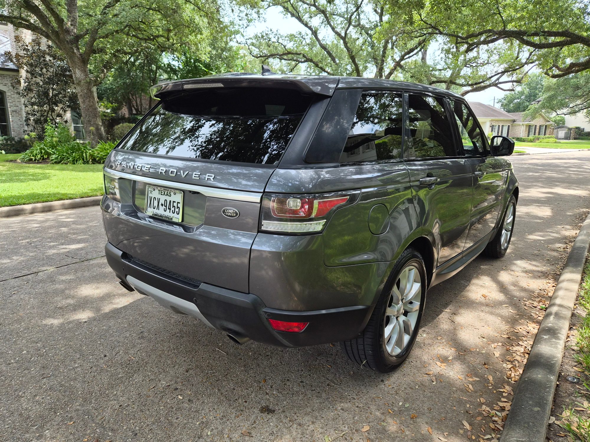 Rear three-quarter view of a grey Range Rover Sport.