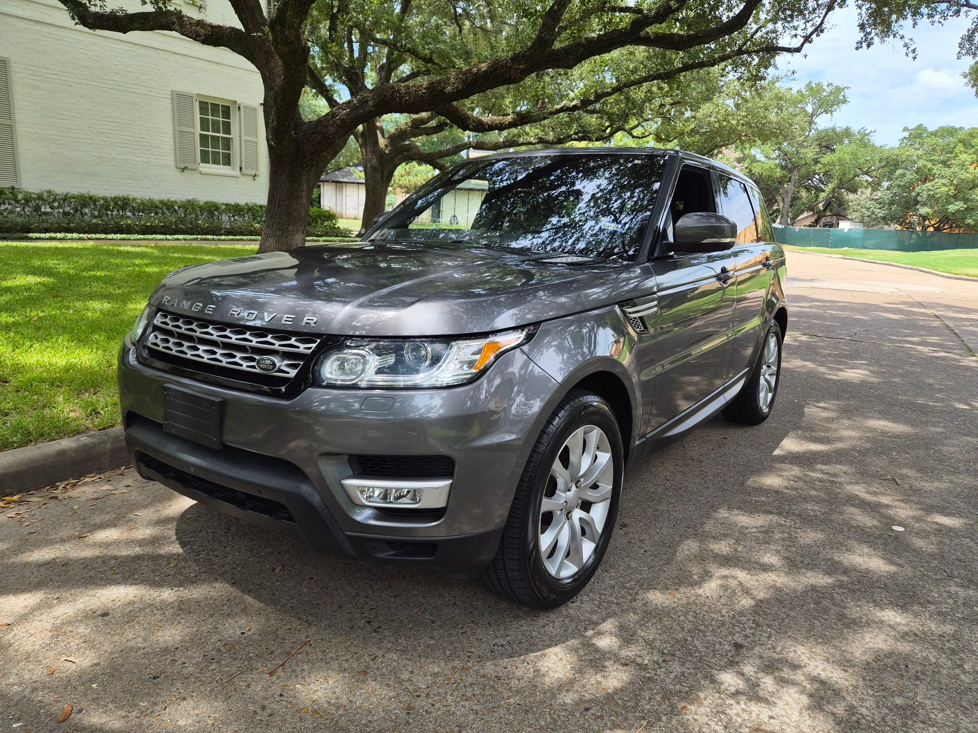 Front three-quarter view of a grey Range Rover Sport parked on a driveway.