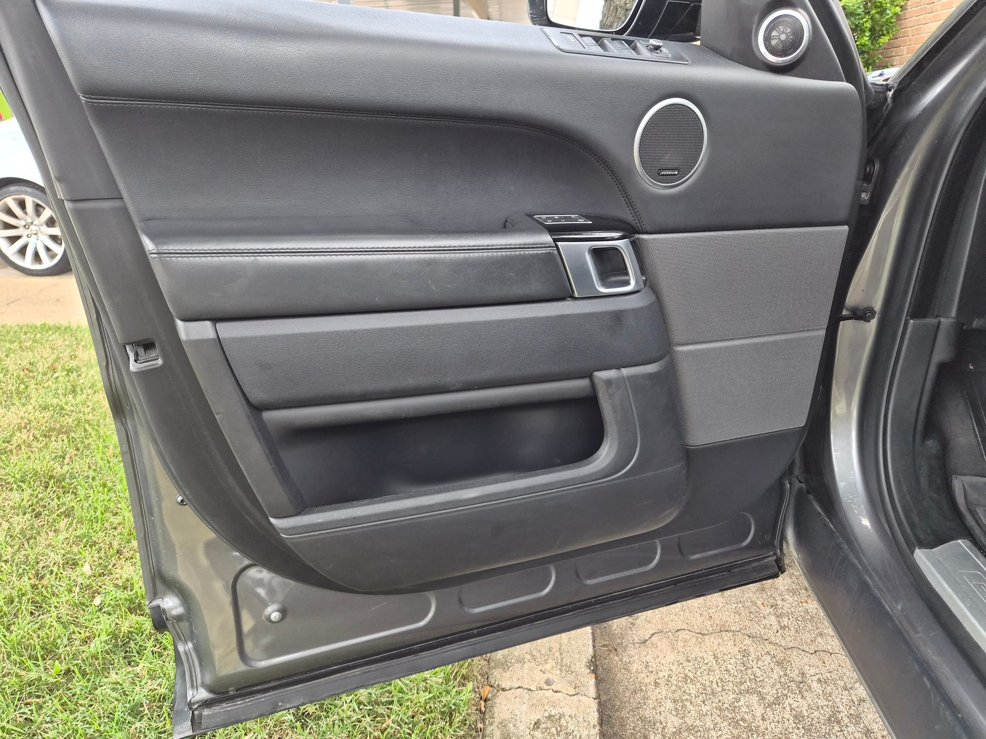 Driver side interior door panel with Meridian audio speakers.