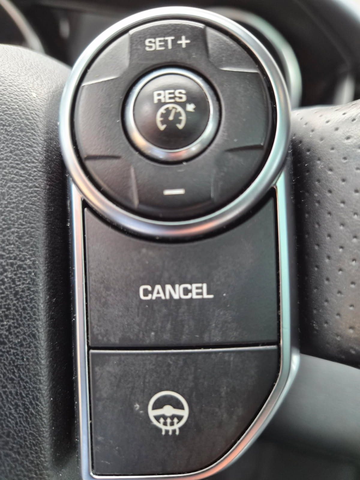 Close-up of steering wheel cruise control and lane assist buttons.